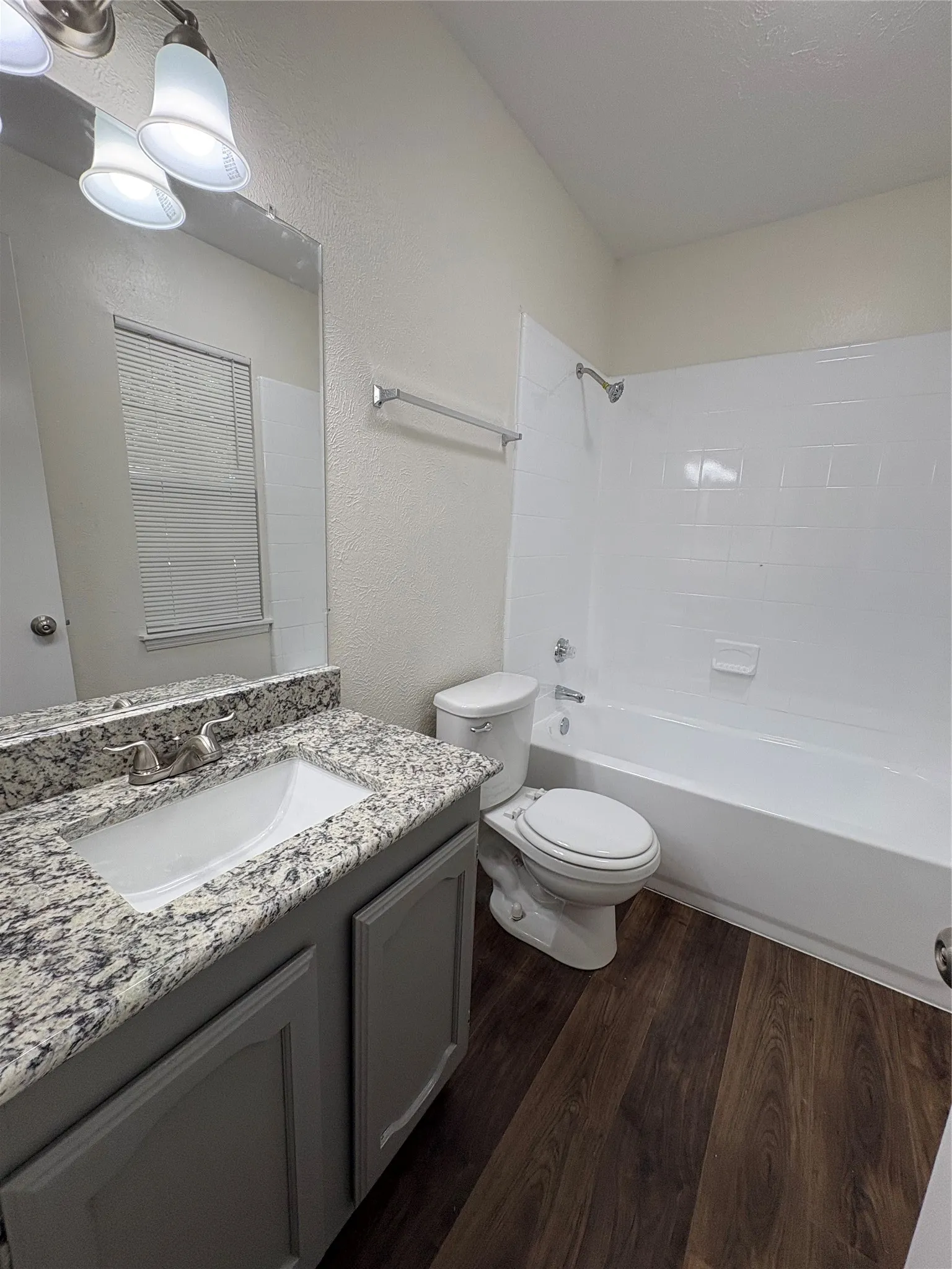 Bathroom featuring a single vanity with stone-finish countertop, undermount sink, and brushed nickel faucet