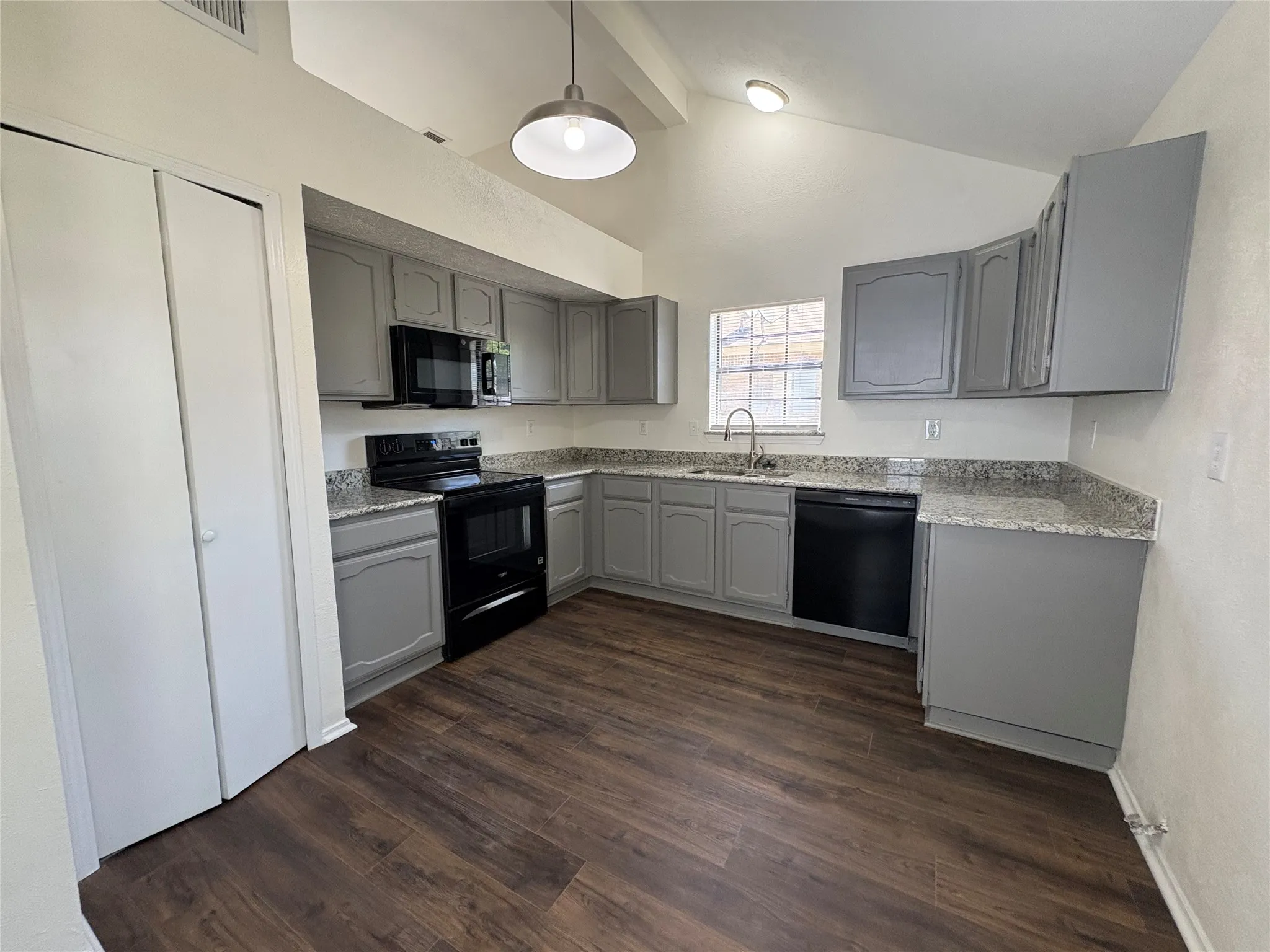 Kitchen featuring wood-finish flooring, gray cabinetry, granite-style countertops, stainless steel sink, and black appliances
