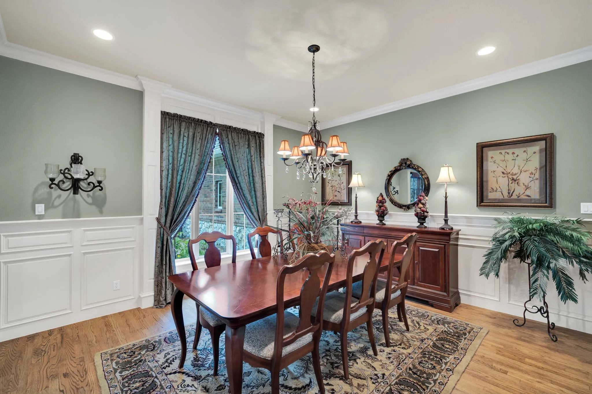Formal dining area featuring hardwood flooring, wainscoting, crown molding, a decorative chandelier, and recessed lighting