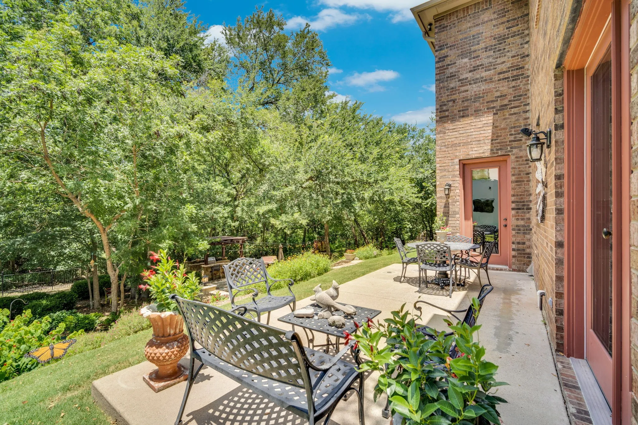Expansive concrete patio bordered by mature trees and a manicured lawn