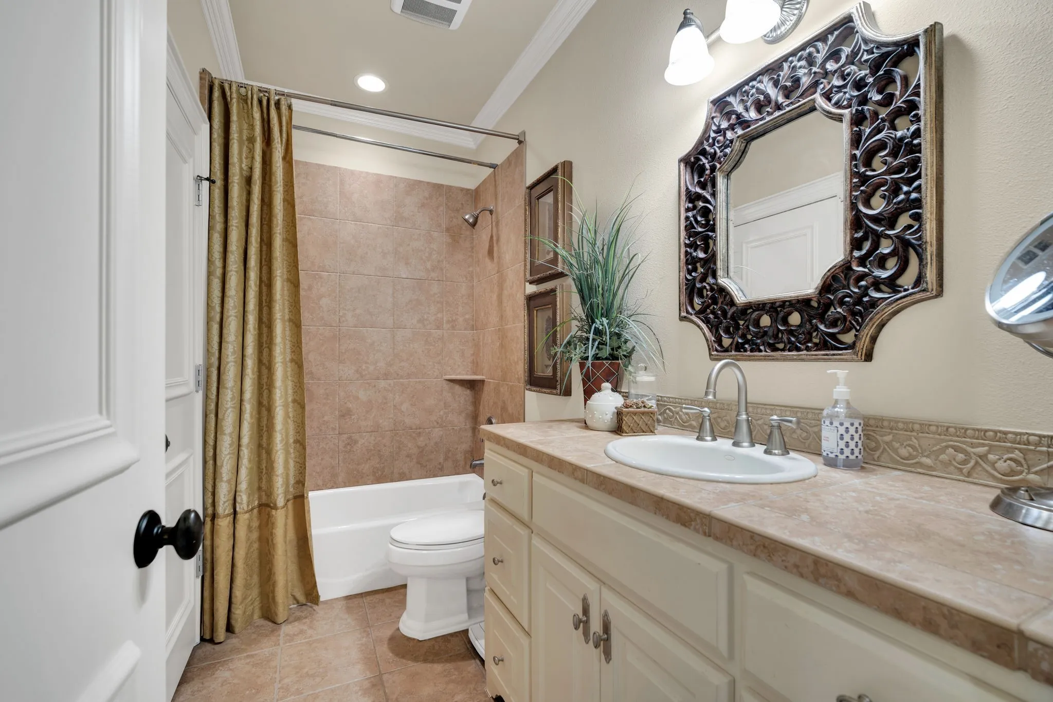 Bathroom featuring a single vanity with an integrated sink, a large ornamental framed mirror, and a three-bulb wall-mounted light fixture
