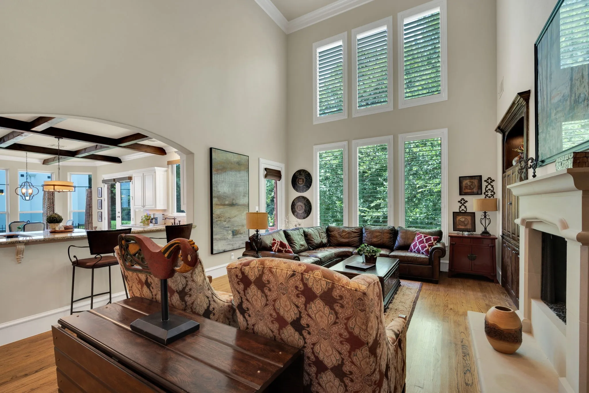 Vaulted living area featuring a fireplace with a mantel, wood-finish flooring, and multiple tall windows