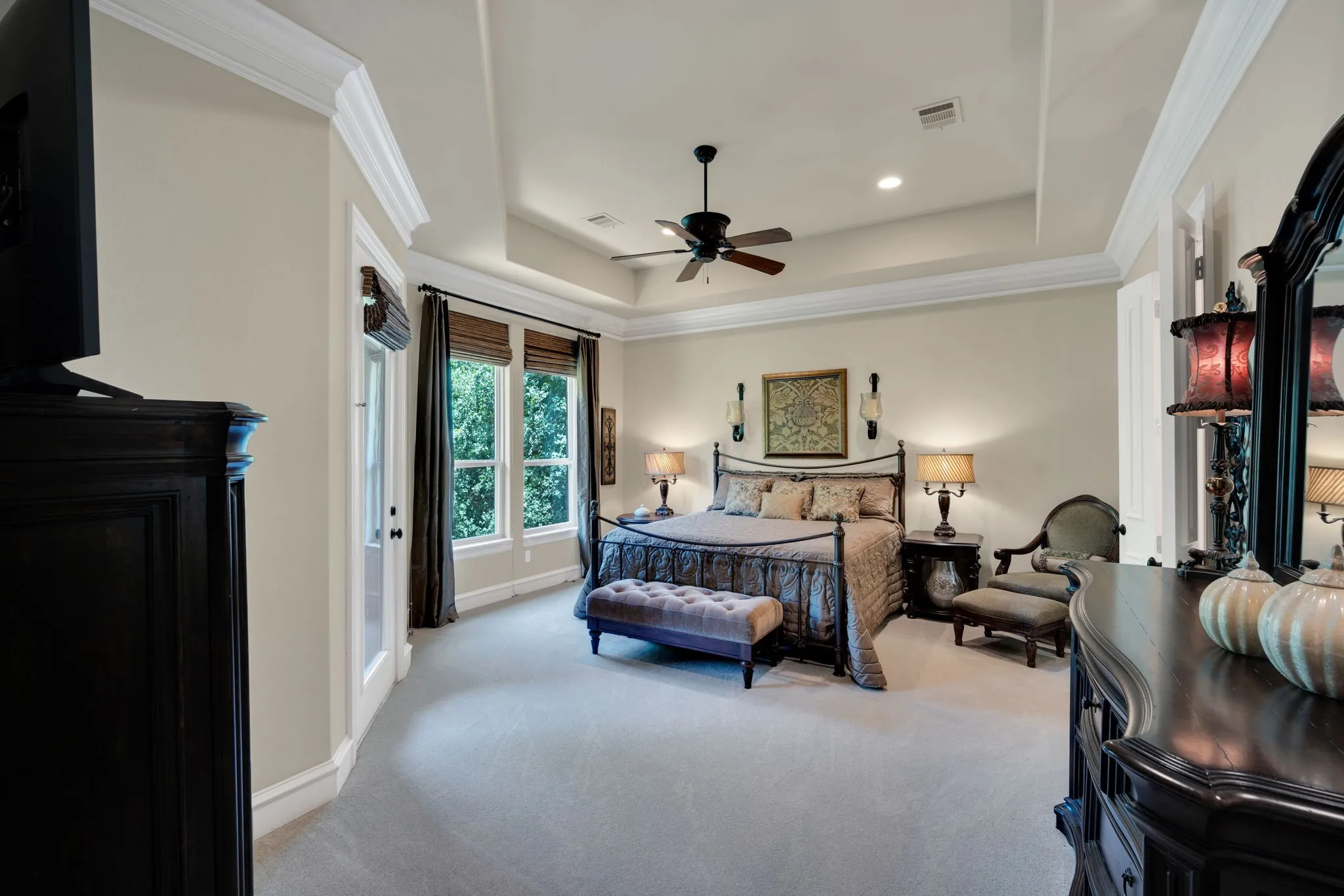 Tray ceiling with crown molding, ceiling fan, recessed lighting, and carpeted flooring