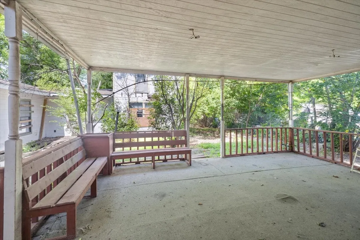 Covered outdoor patio area featuring a concrete slab, wood-paneled ceiling, and painted wood railings