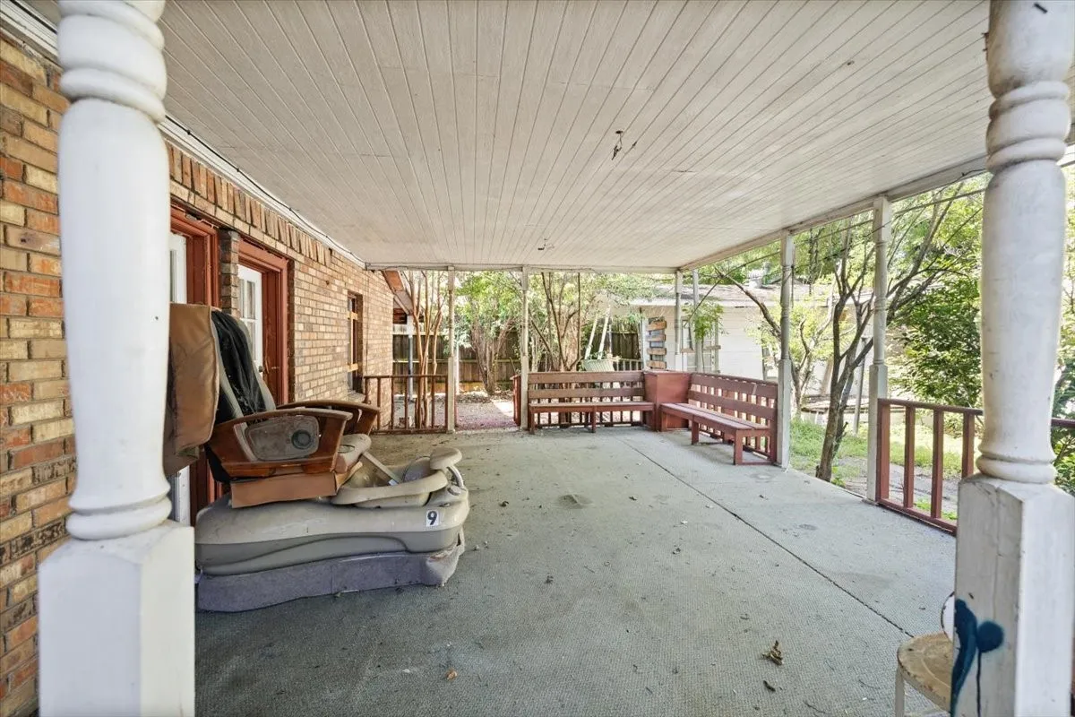 Expansive covered porch featuring a brick exterior, white paneled ceiling, and built-in wooden benches