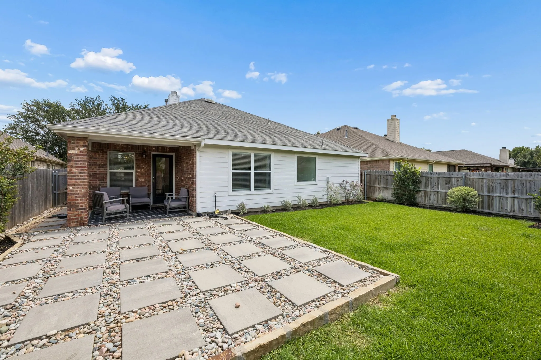 The exterior features a landscaped backyard with a covered porch and an additional open patio.