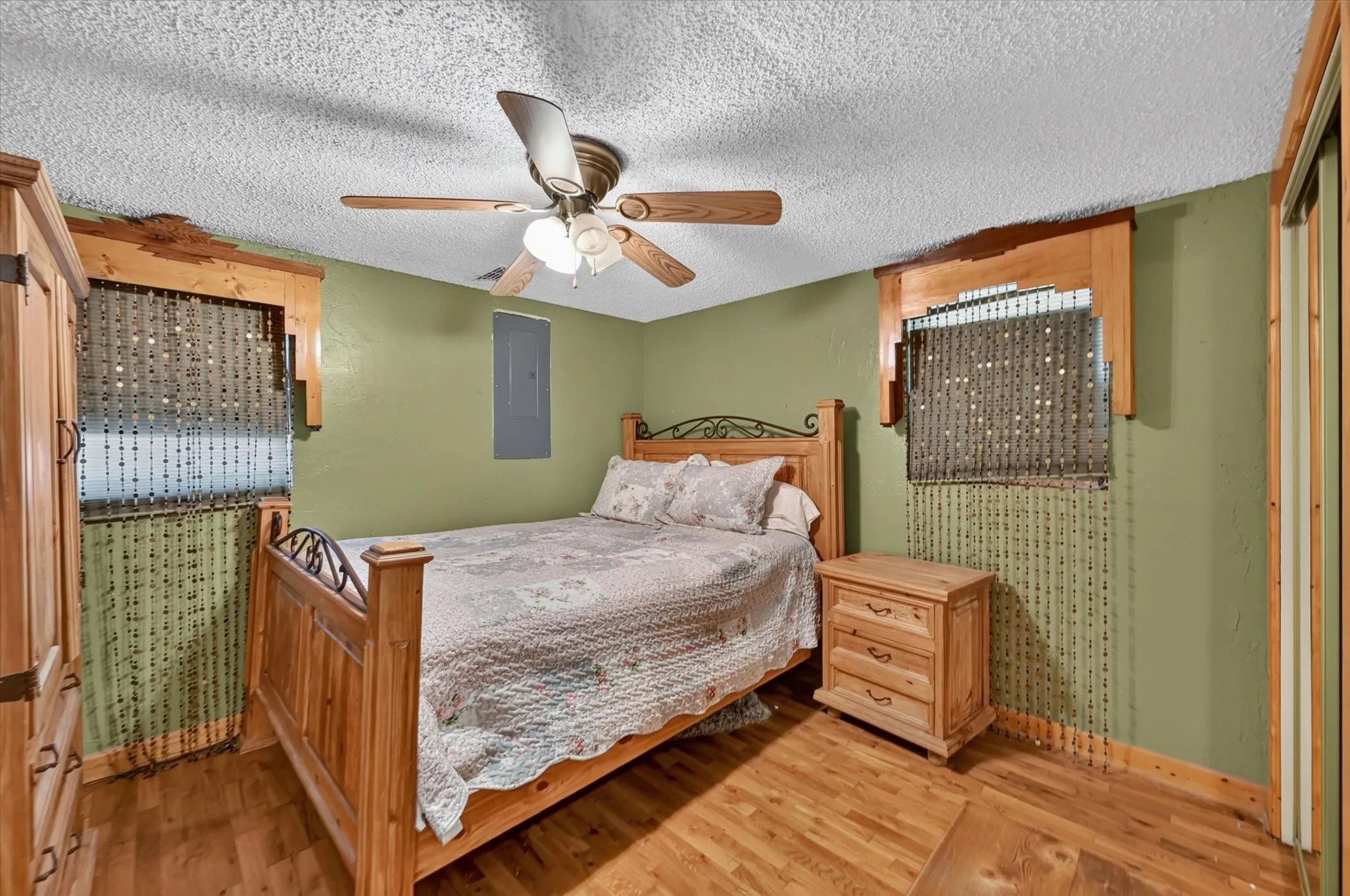 Interior room featuring wood-finish flooring, a ceiling fan with light fixture, and green painted walls