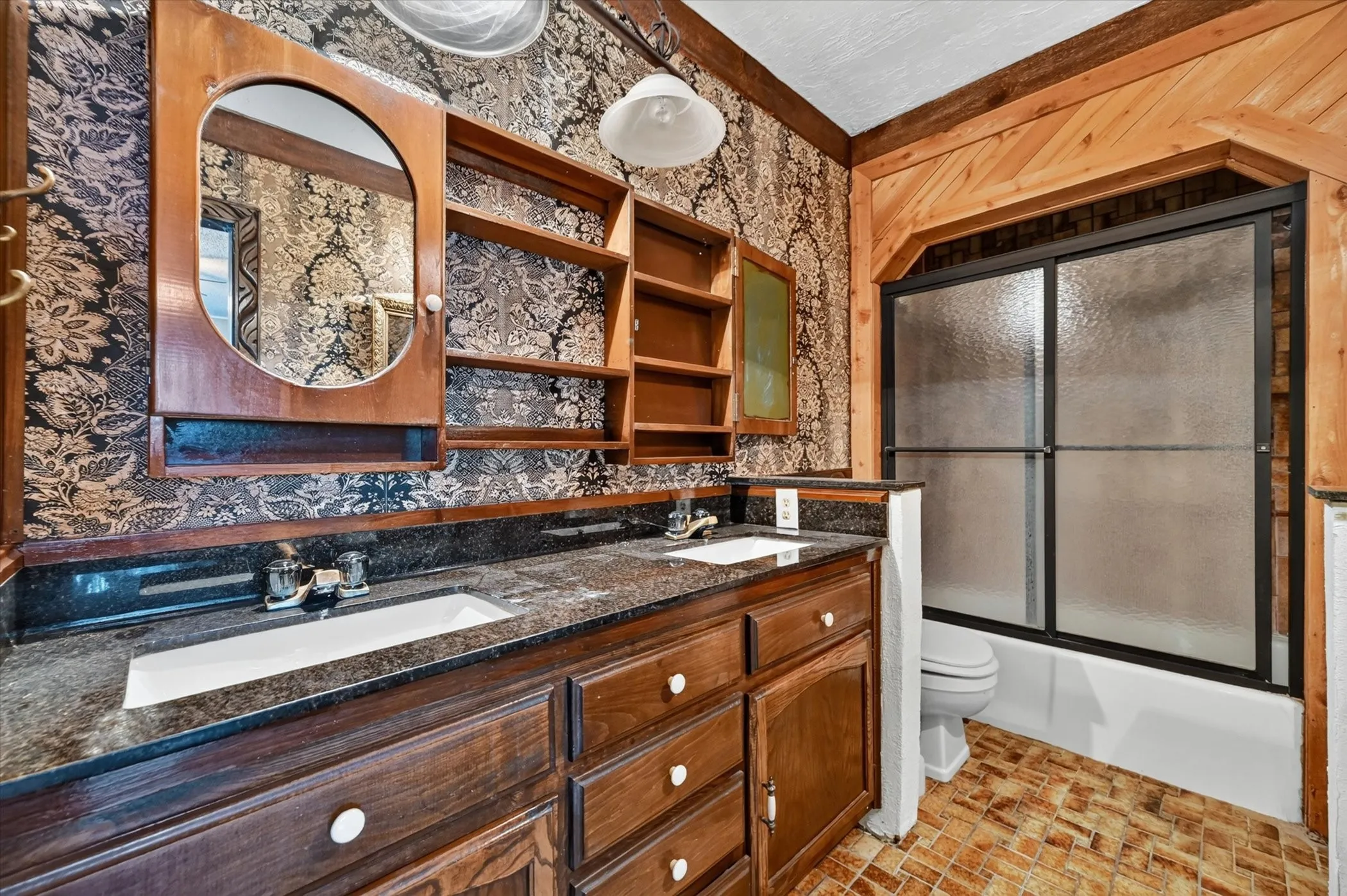 Bathroom featuring a wood-finish double vanity with integrated sinks and a dark speckled countertop