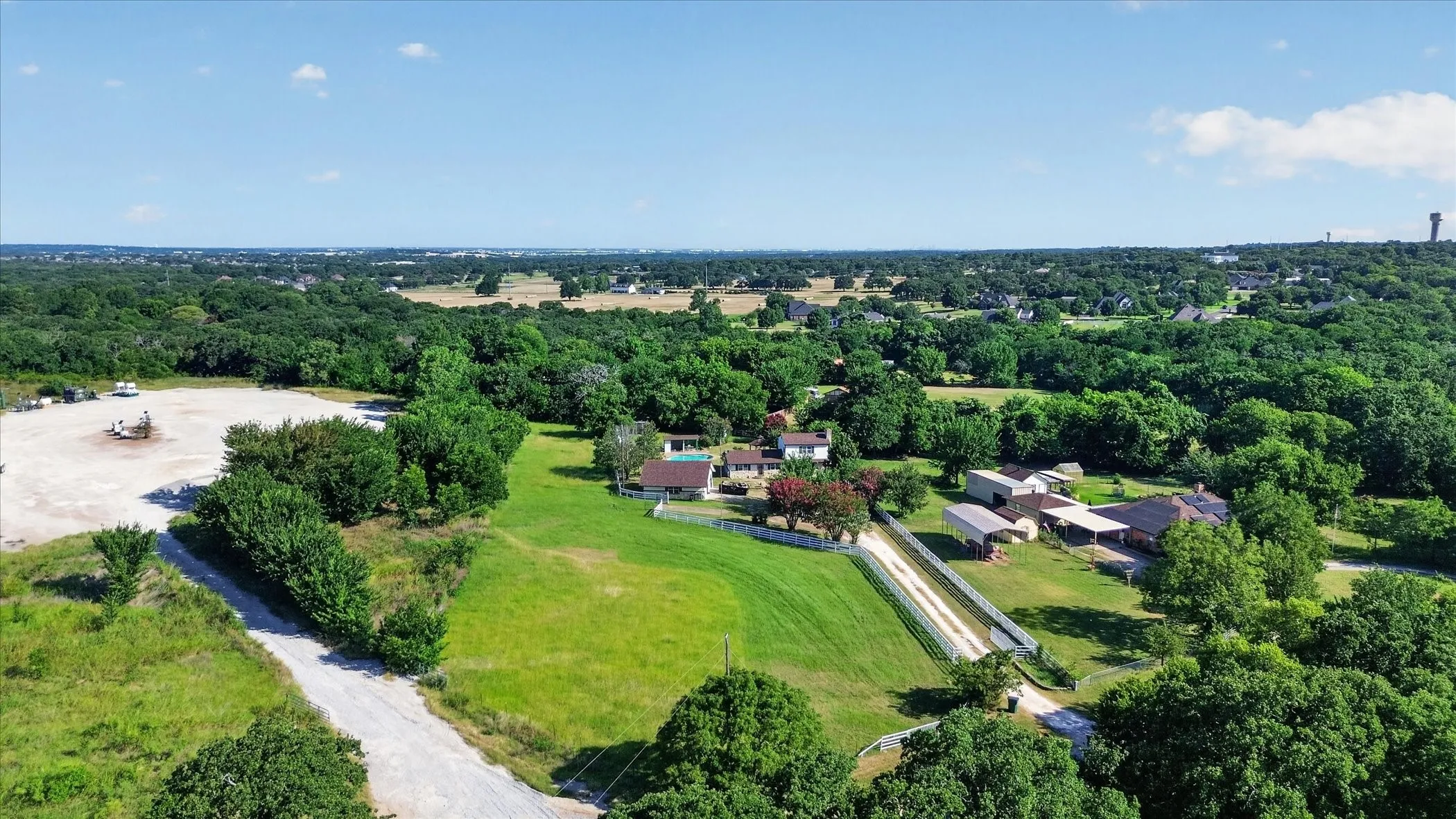 Expansive rural property featuring a main residence, multiple outbuildings, and a gravel driveway