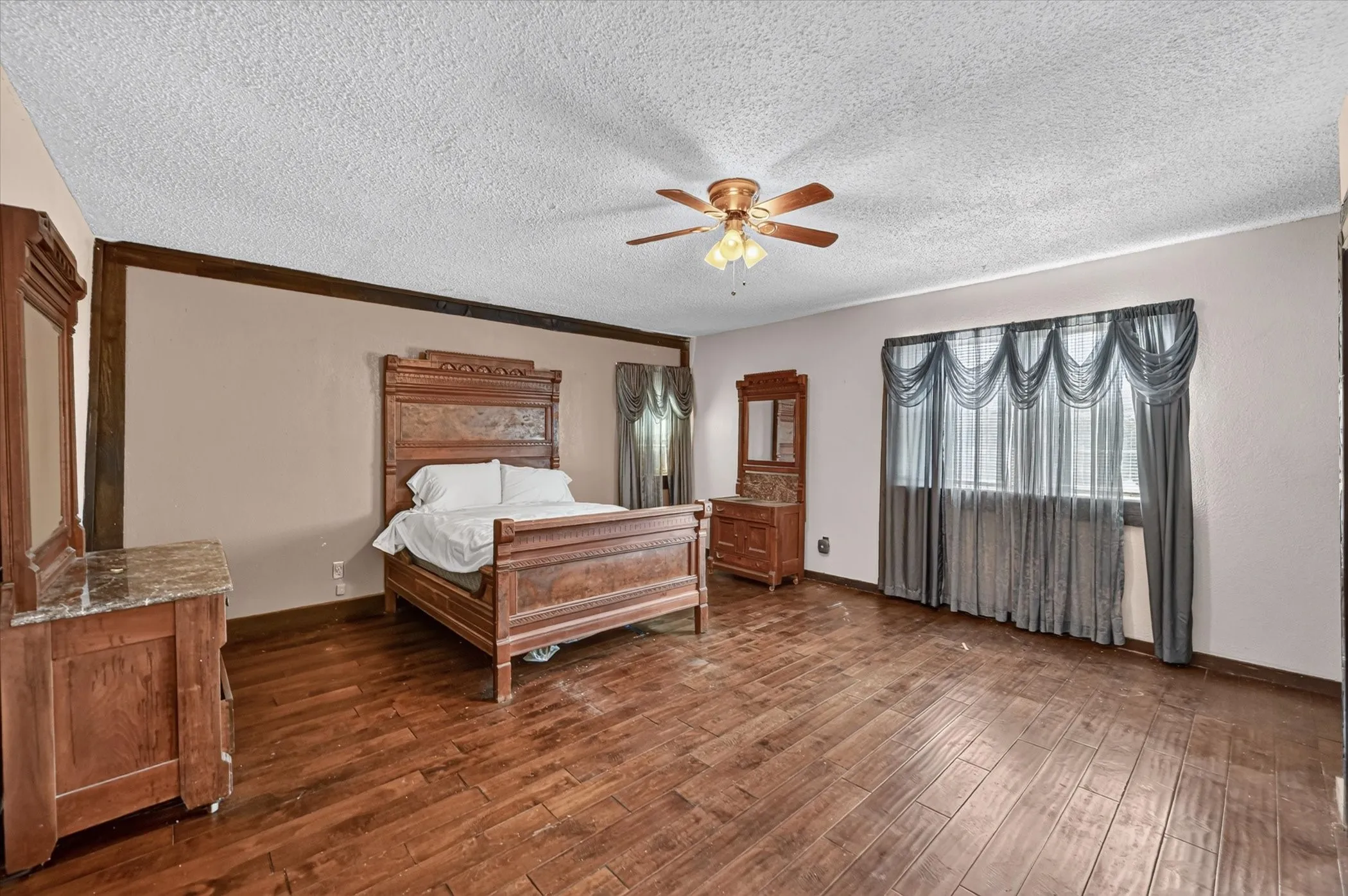 Spacious room featuring wood-finish flooring, a textured ceiling, and a ceiling fan with integrated lighting