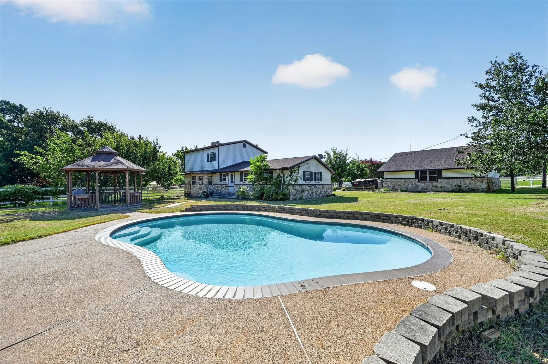 Freeform swimming pool with integrated steps, surrounded by an exposed aggregate concrete deck