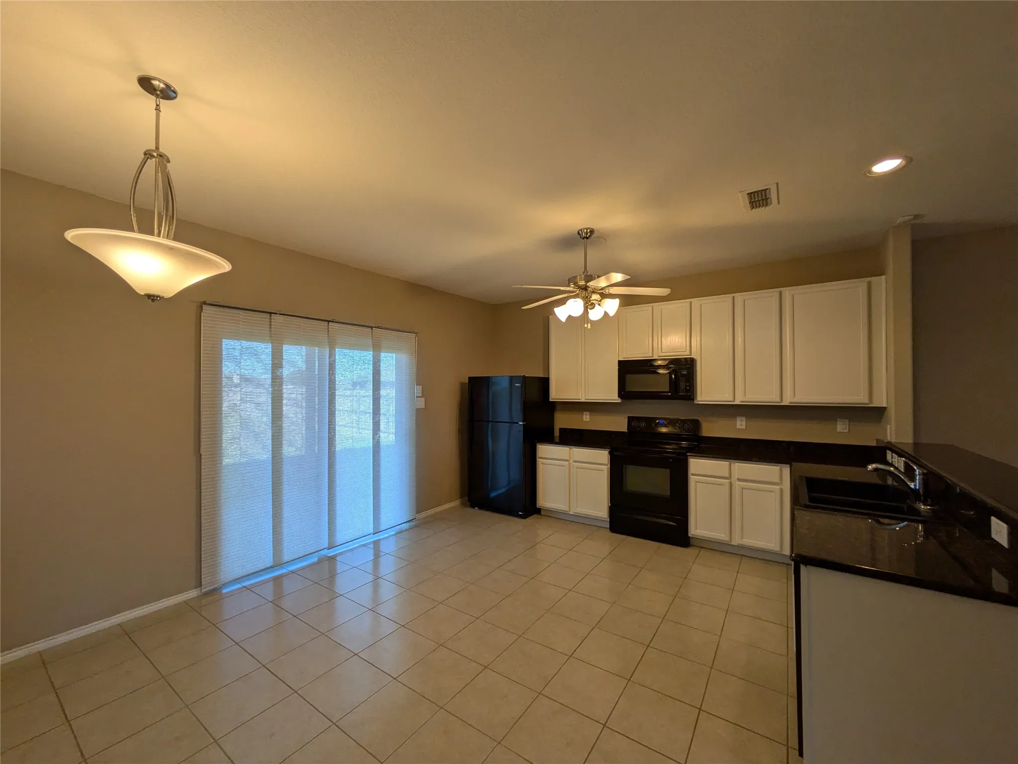 Kitchen featuring hanging light fixtures, white cabinetry, black appliances, ceiling fan, and sink