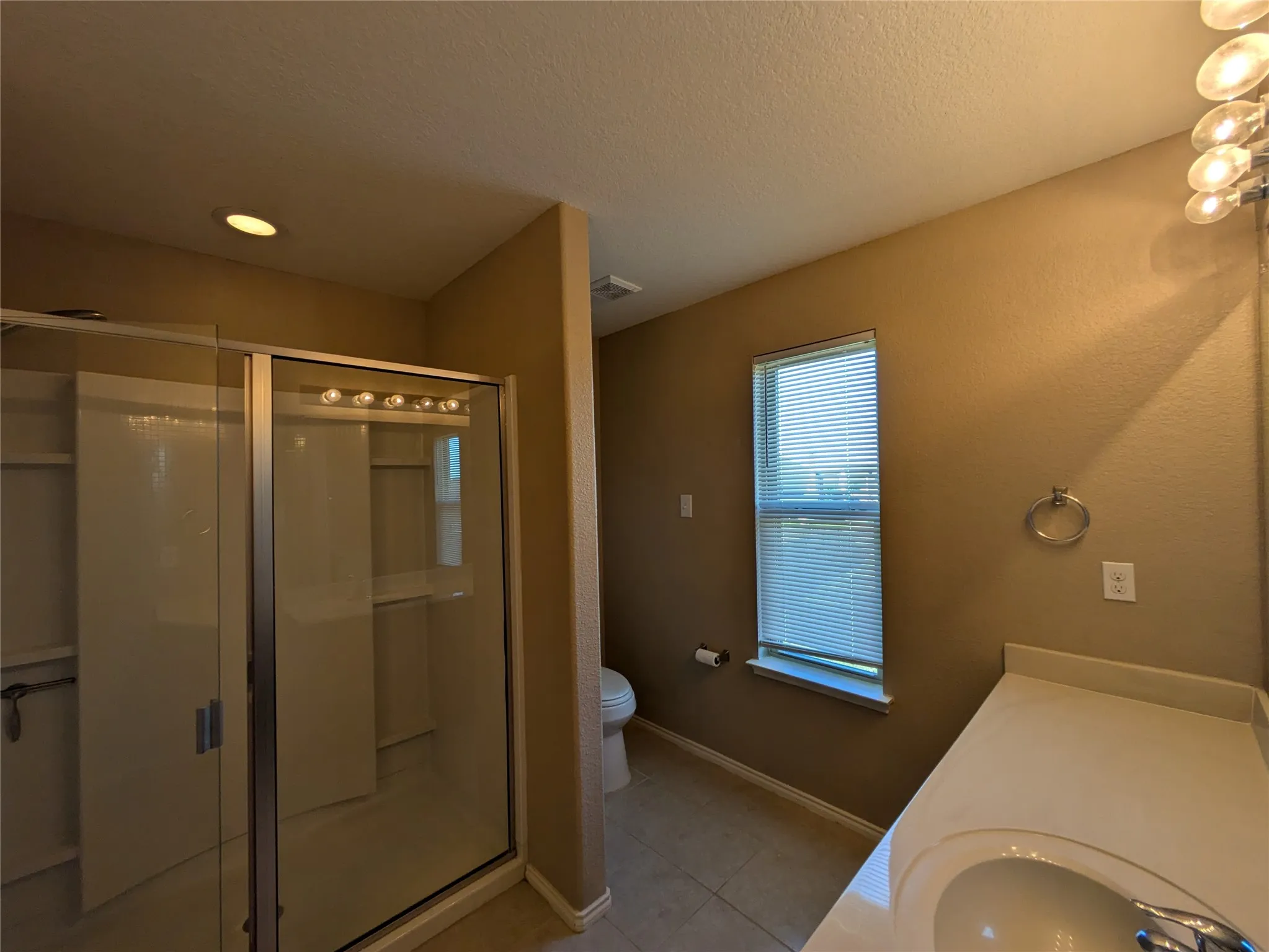 Bathroom featuring a textured ceiling, a shower with door, tile patterned floors, vanity, and toilet