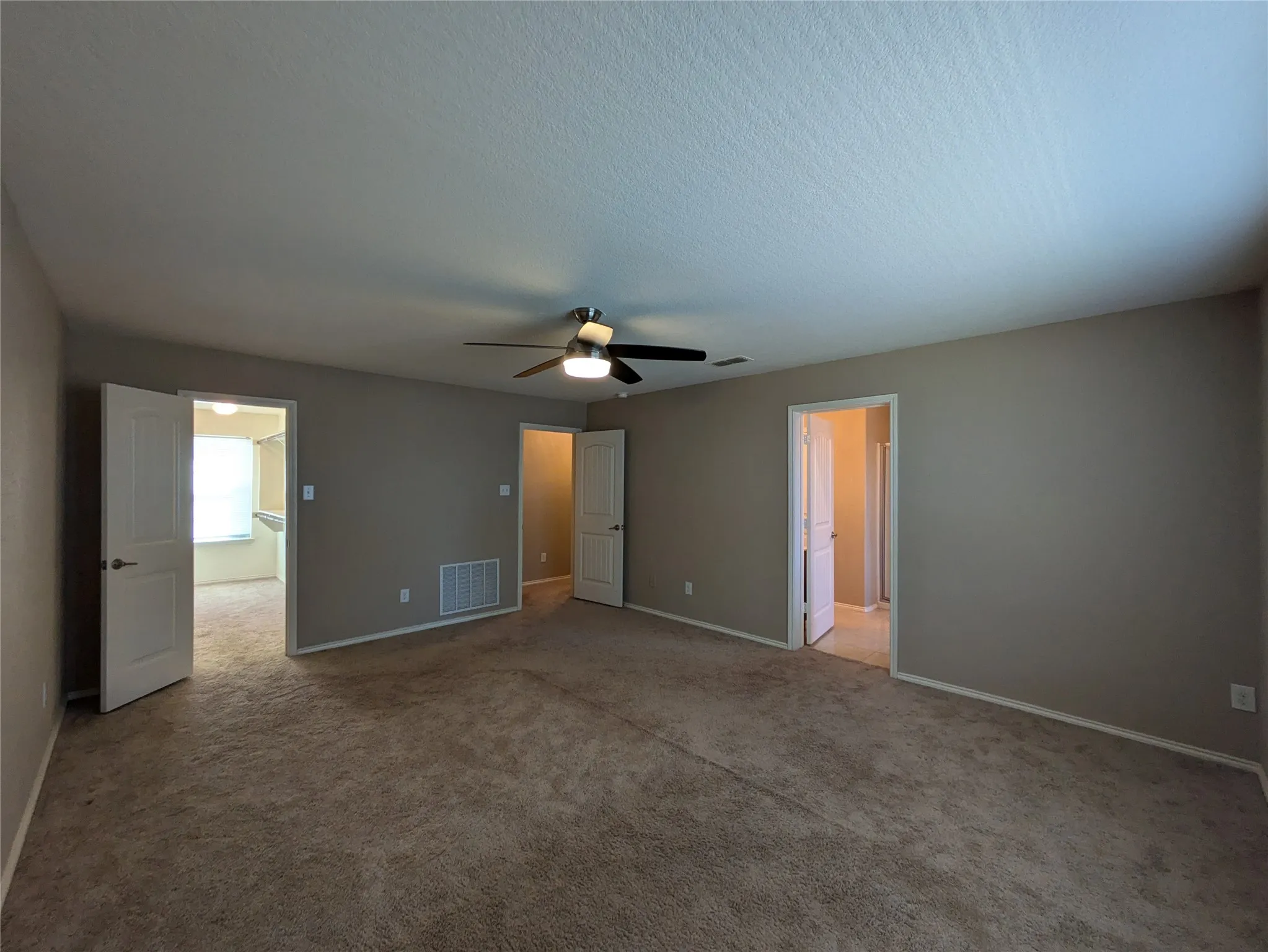 Carpeted empty room with ceiling fan and a textured ceiling