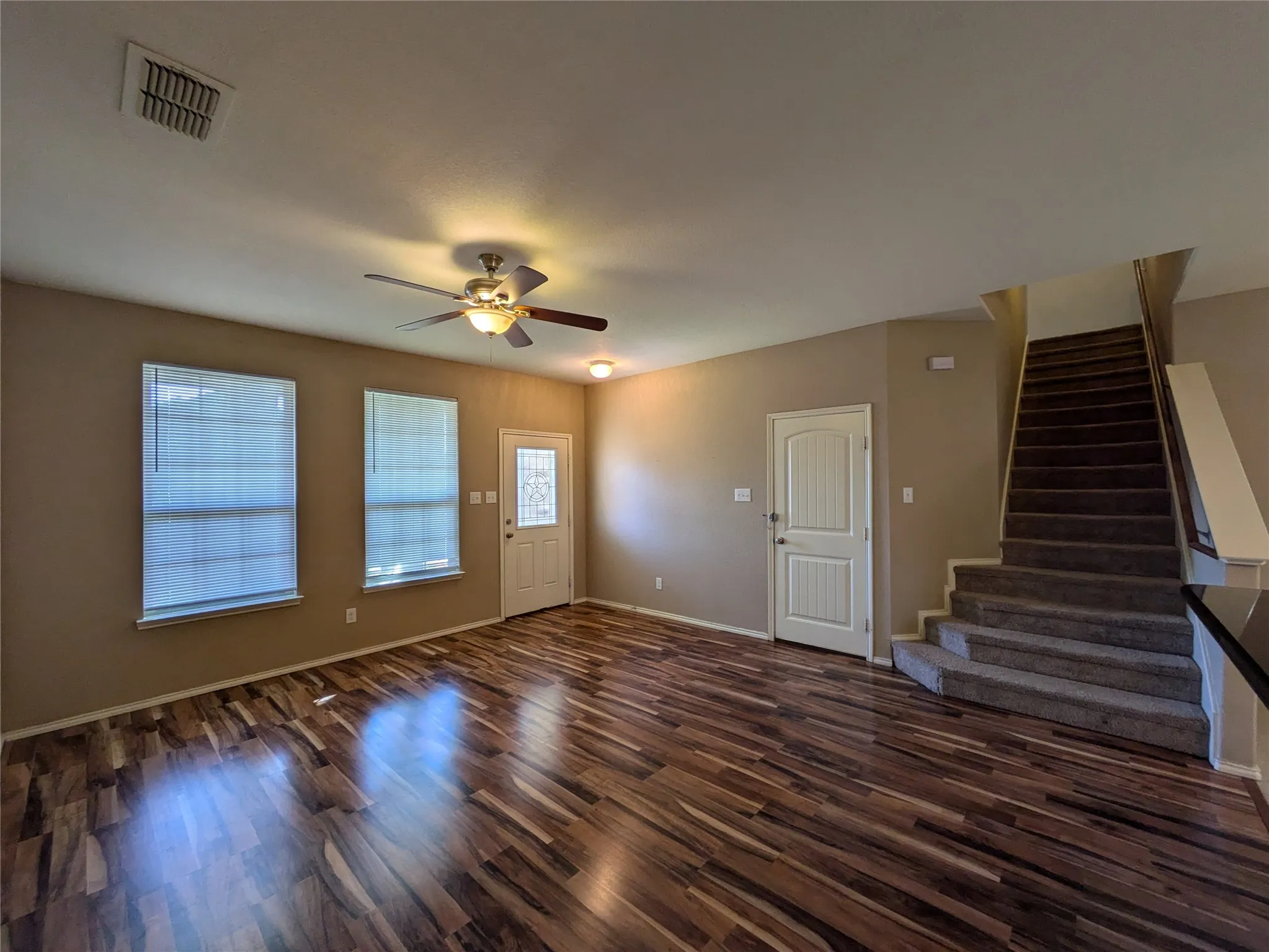 Unfurnished living room featuring ceiling fan and dark wood-type flooring