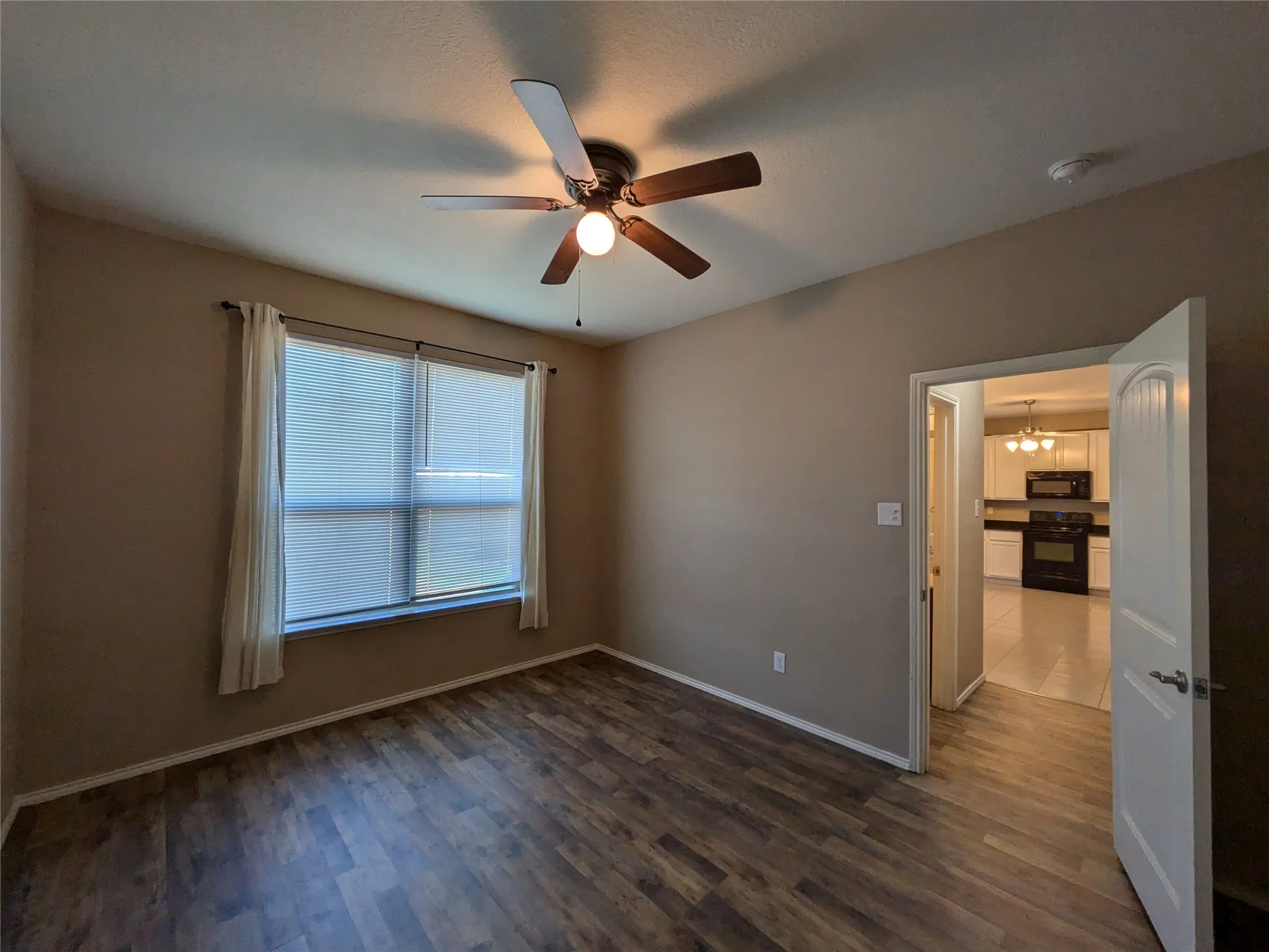 Unfurnished room with ceiling fan with notable chandelier and dark hardwood / wood-style floors