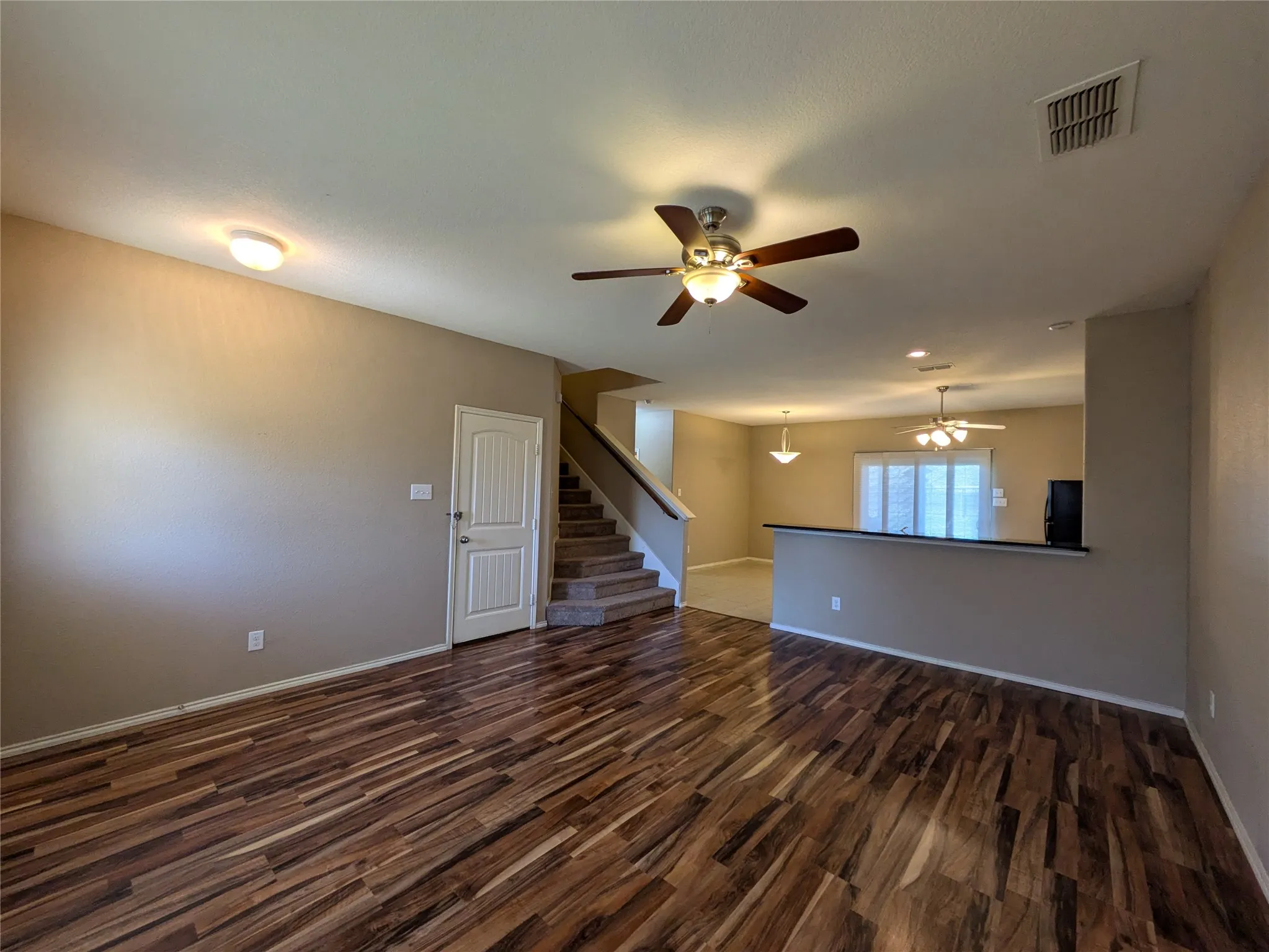 Unfurnished living room featuring ceiling fan and dark hardwood / wood-style flooring