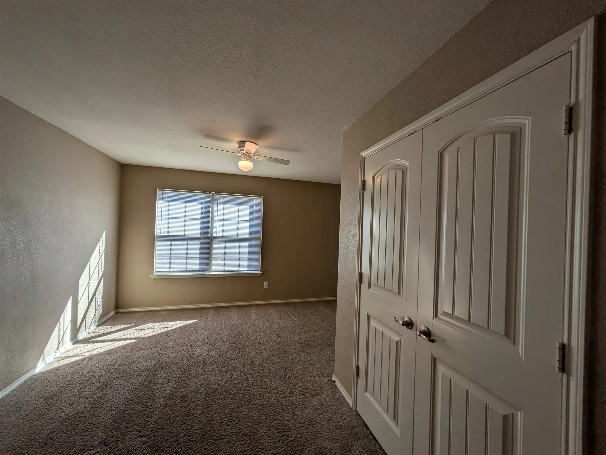 Spare room with a textured ceiling, carpet flooring, and ceiling fan