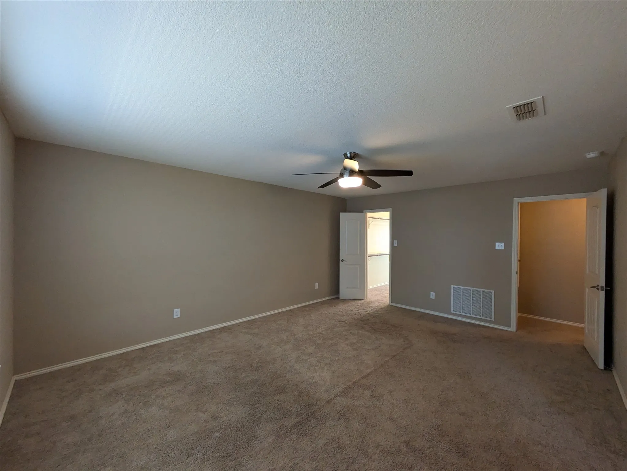 Unfurnished room featuring ceiling fan, carpet floors, and a textured ceiling