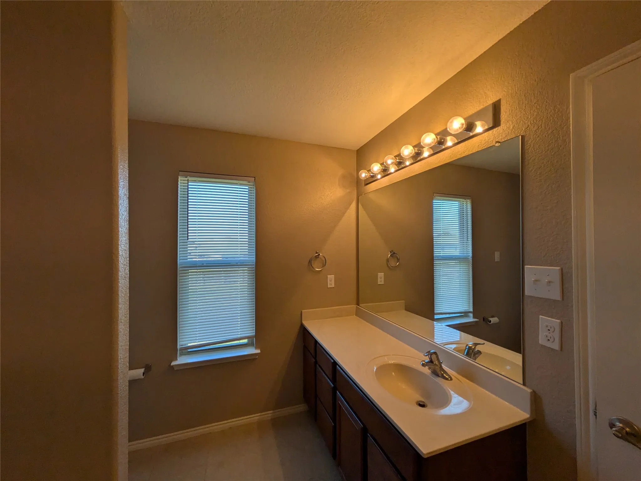 Bathroom with a textured ceiling, vanity, and plenty of natural light