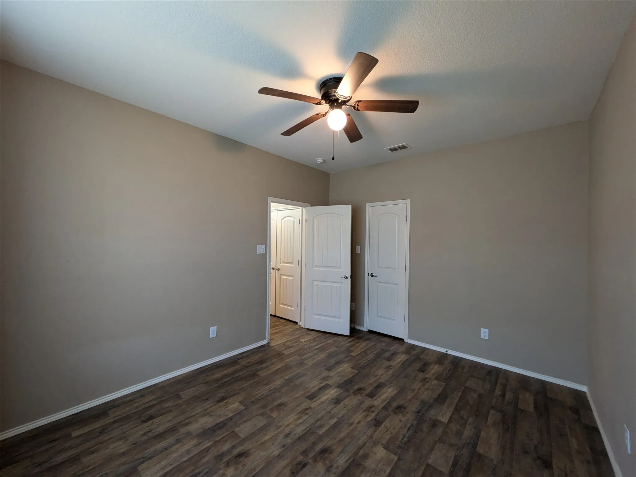 Unfurnished bedroom featuring ceiling fan and dark wood-type flooring