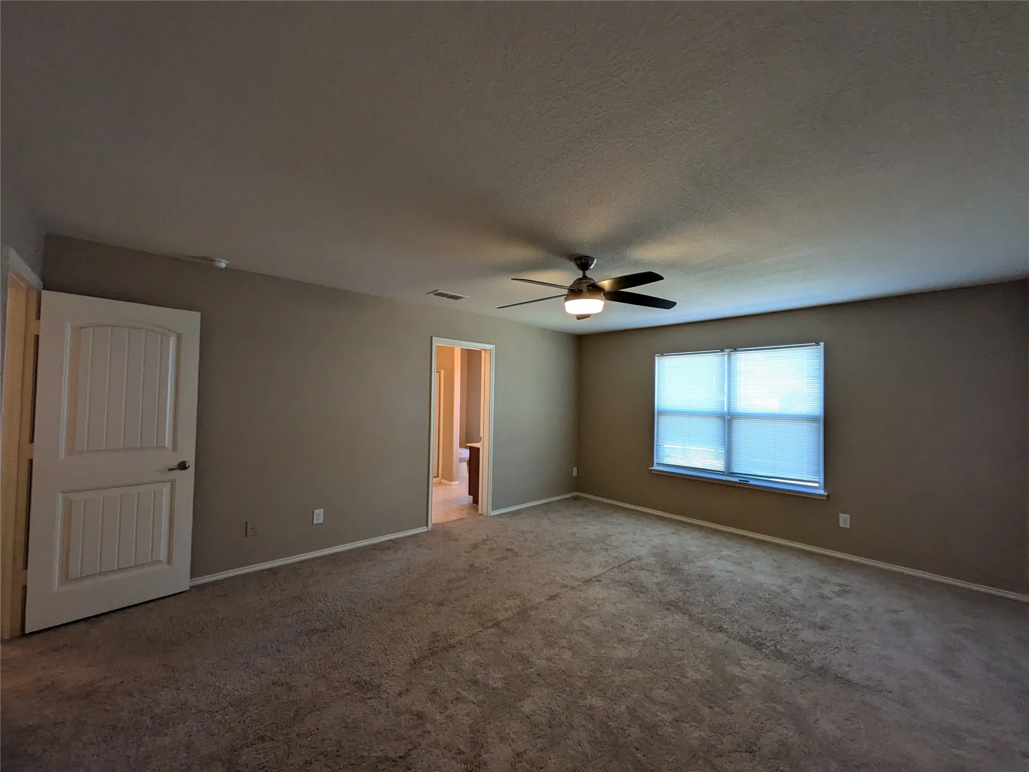 Carpeted empty room featuring a textured ceiling and ceiling fan