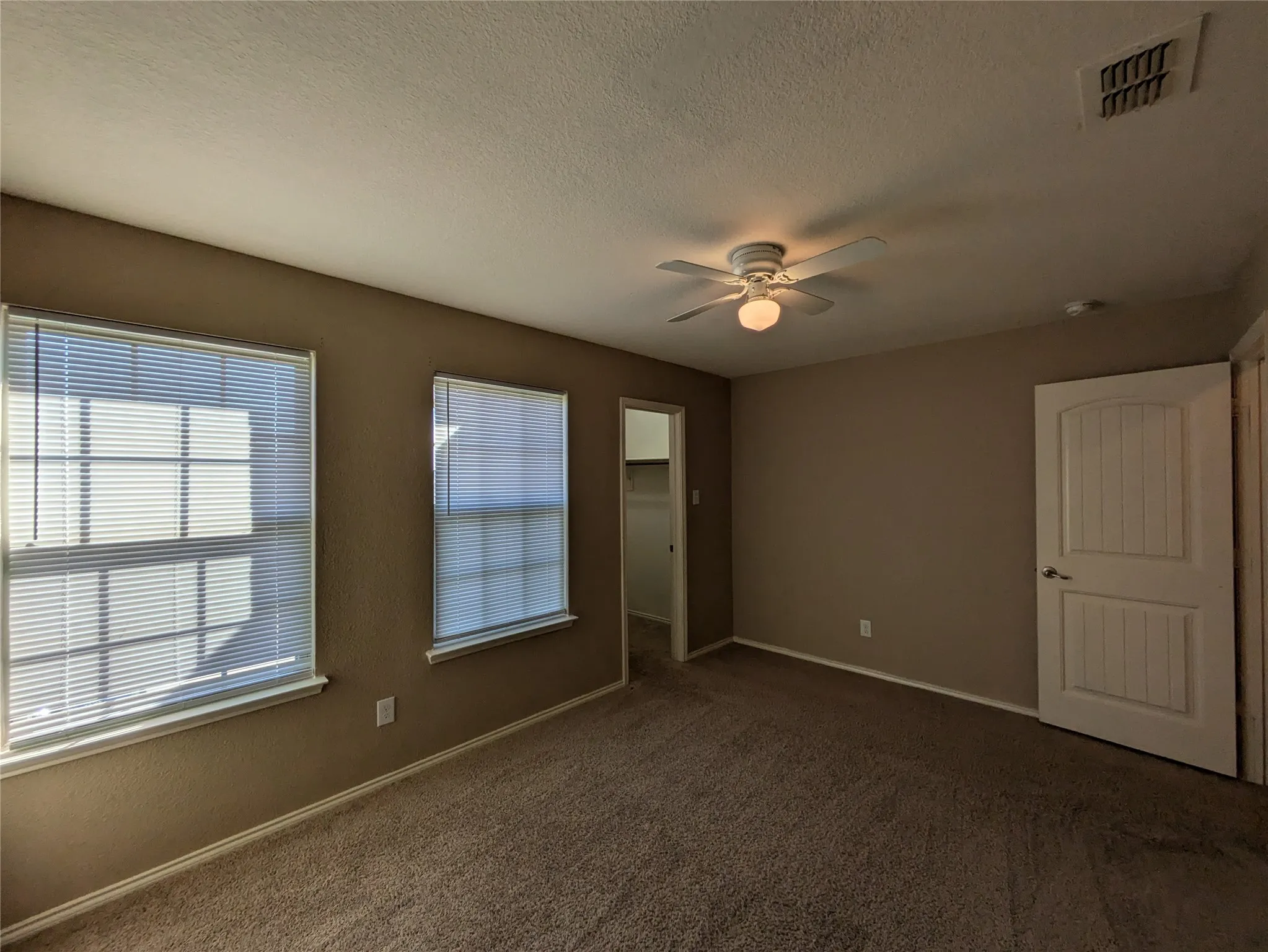 Carpeted empty room featuring ceiling fan and a textured ceiling