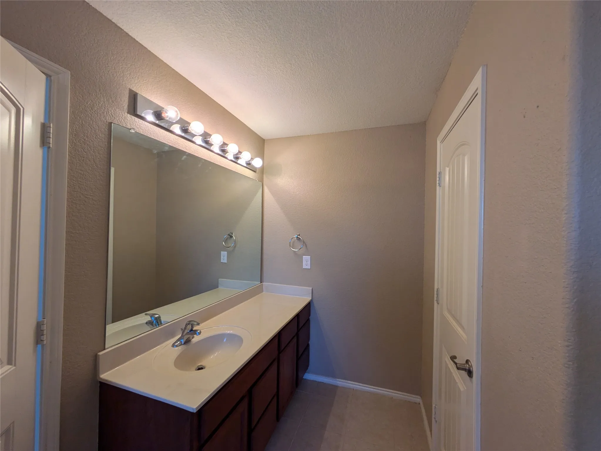 Bathroom with tile patterned floors, a textured ceiling, and vanity