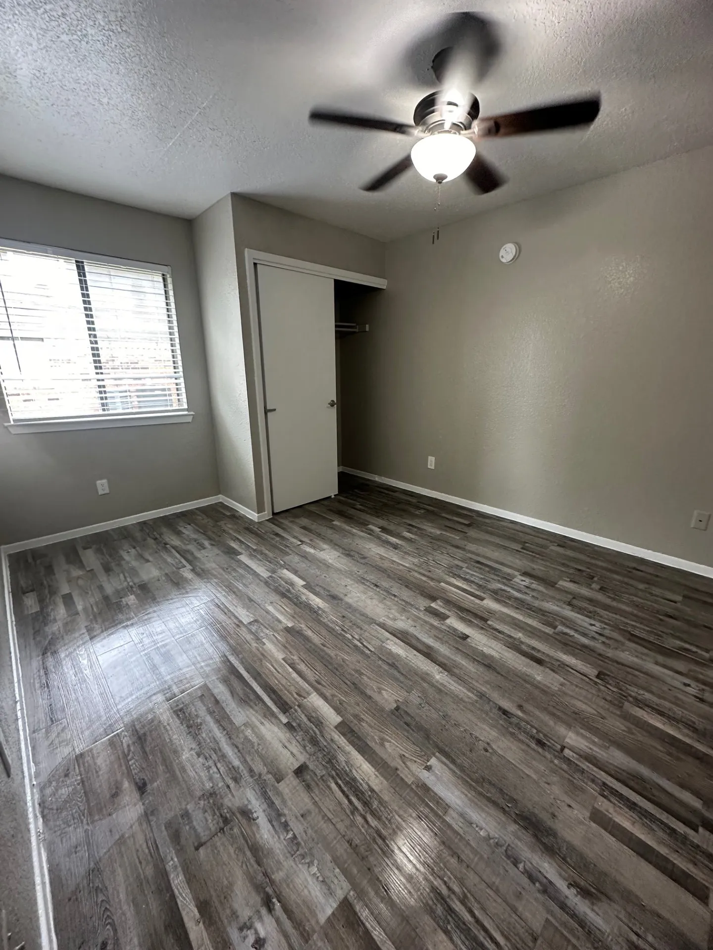 Room featuring wood-finish flooring, neutral wall paint, and a ceiling fan with integrated lighting