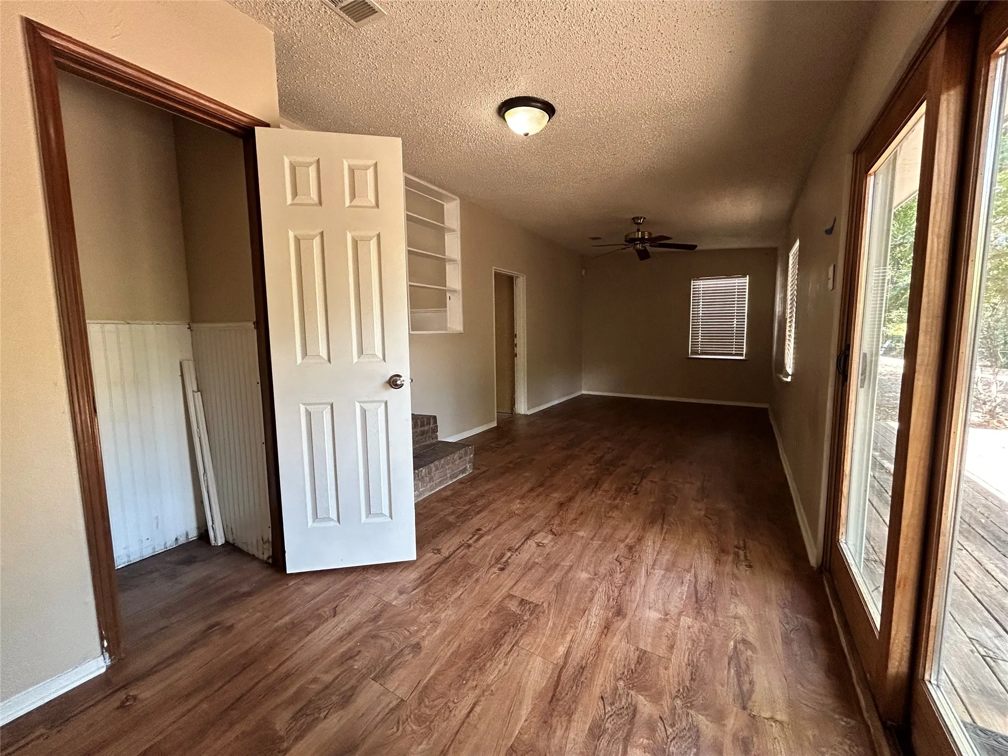 Wood-finish flooring throughout, ceiling fan, built-in shelving, and sliding glass door