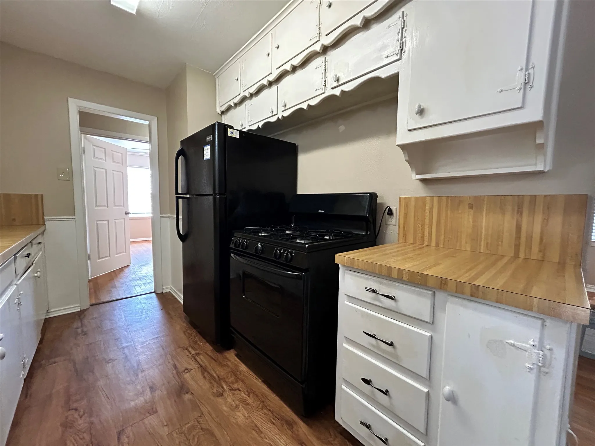 Kitchen featuring wood-finish flooring, white cabinetry, and wood countertops