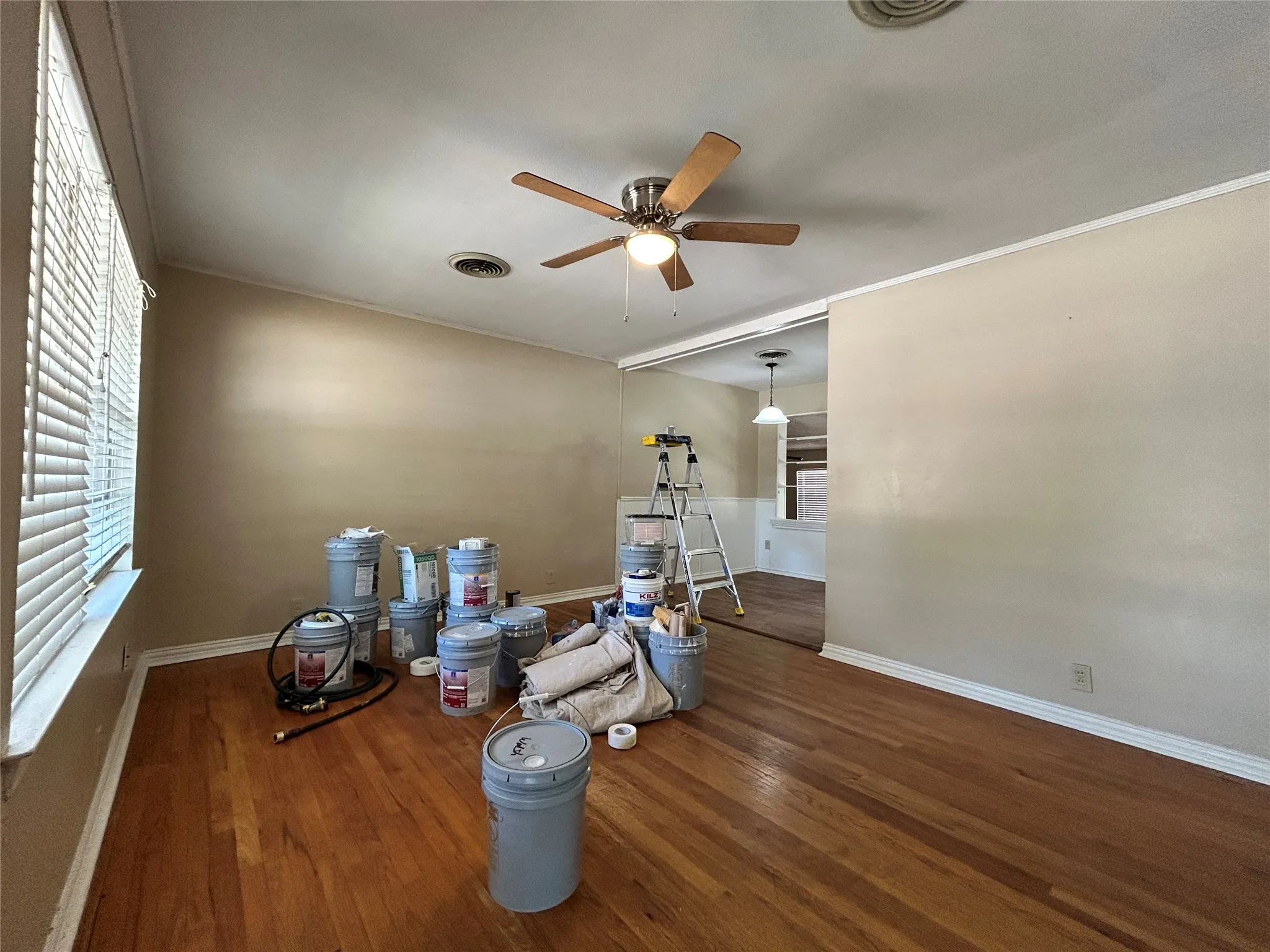 Wood-finish flooring, ceiling fan with integrated lighting, window with blinds, and neutral wall tones