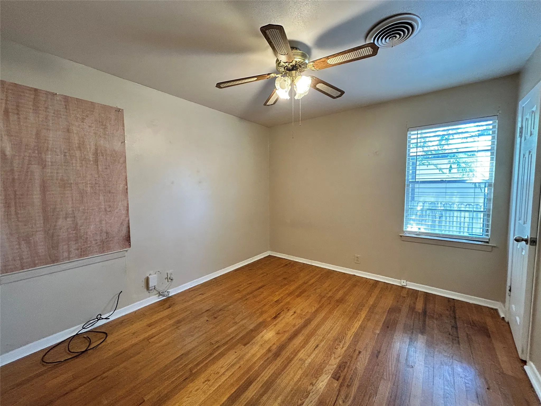 Wood-finish flooring, ceiling fan with integrated lighting, single window with blinds, and painted walls