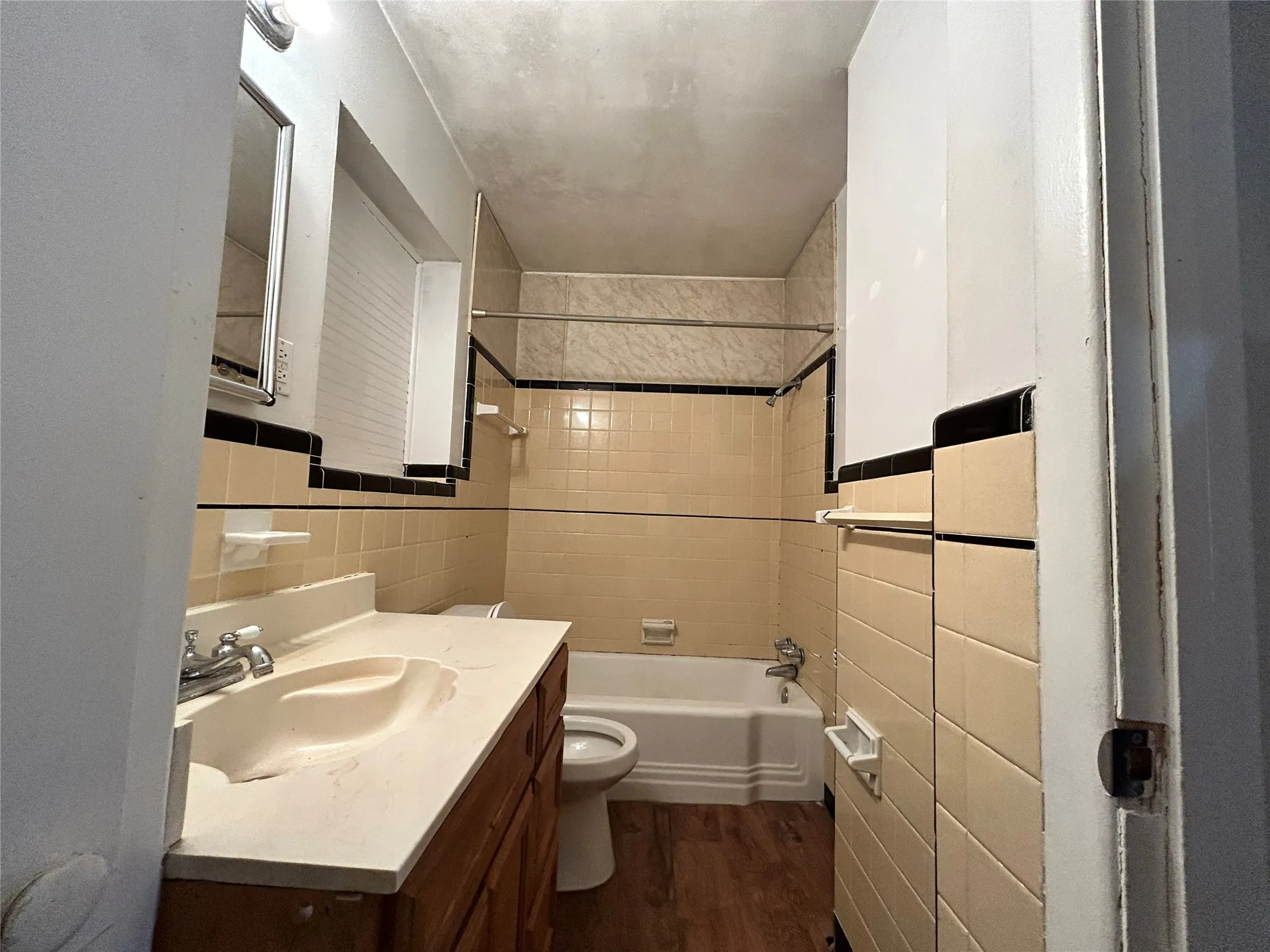 Wood-finish flooring, full bathtub with a shower, and a built-in vanity with an integrated sink