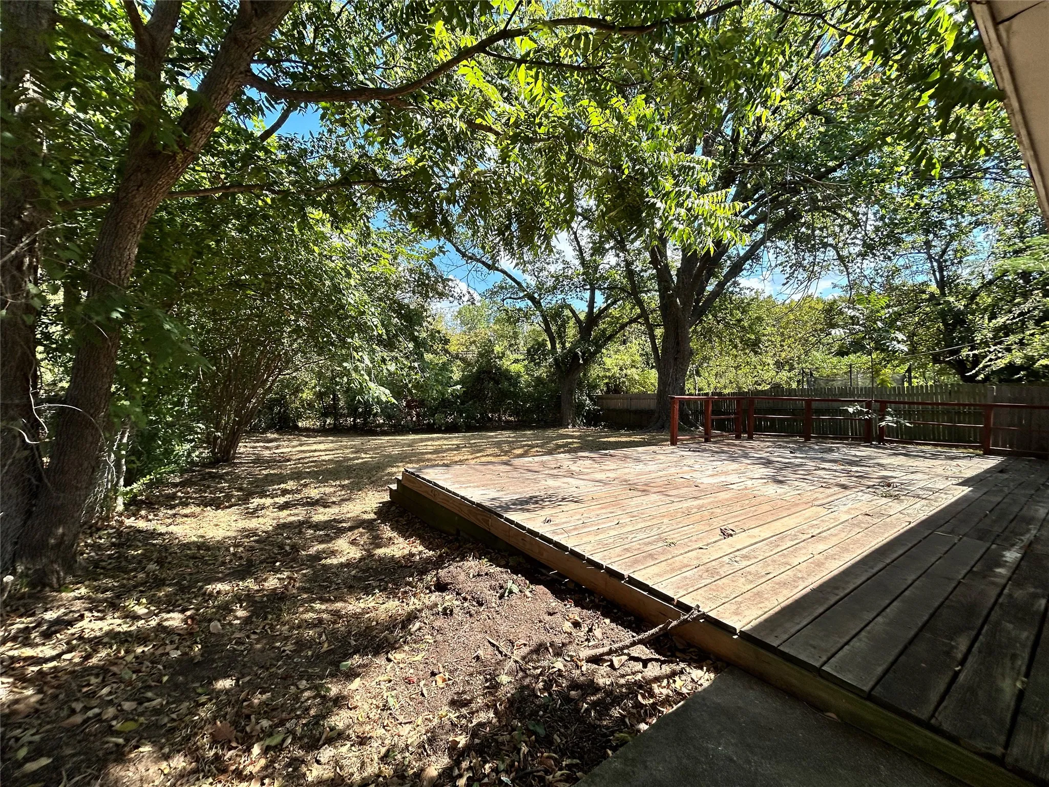 Expansive backyard with a wooden deck and mature trees