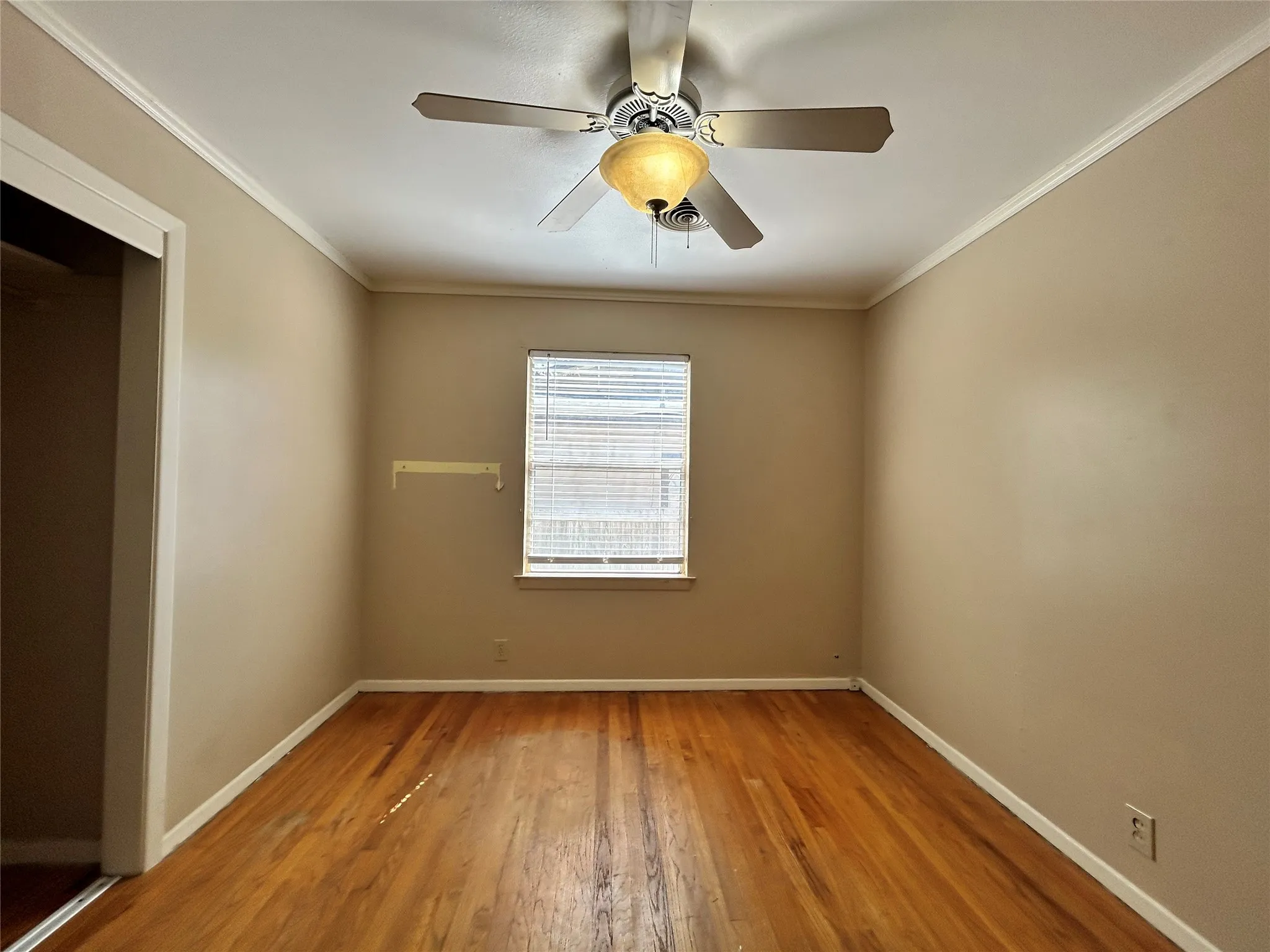 Hardwood flooring, crown molding, ceiling fan with light fixture, window with blinds, and white trim