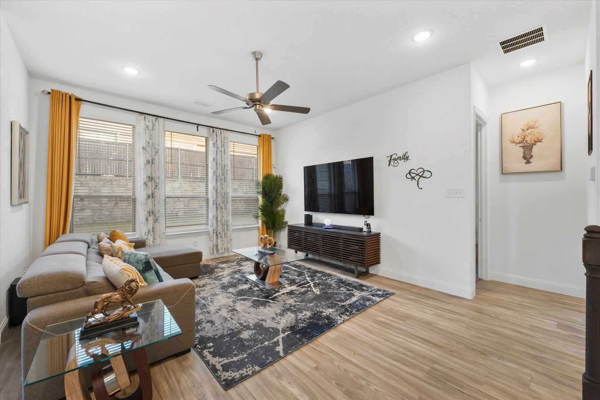 Spacious living area featuring light wood-finish flooring, recessed lighting, and a ceiling fan