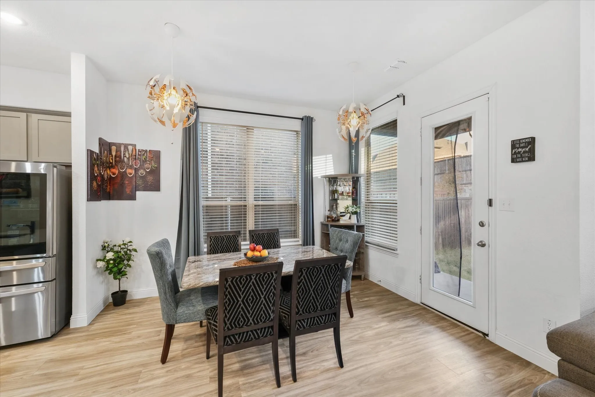 Dining area featuring wood-finish flooring, a large window with blinds and drapes, and a glass-paned exterior door