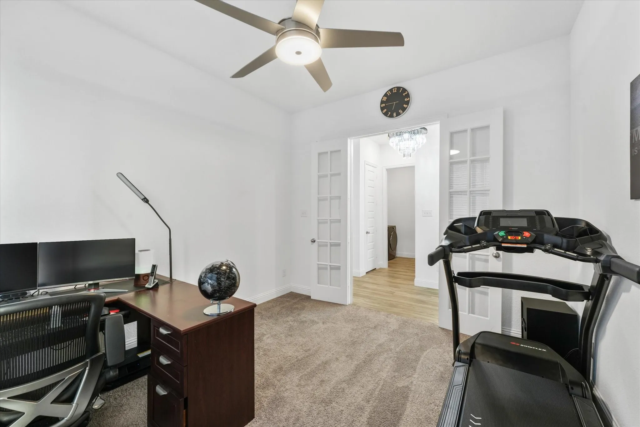 Carpeted room featuring a ceiling fan with integrated lighting, white walls, and French doors