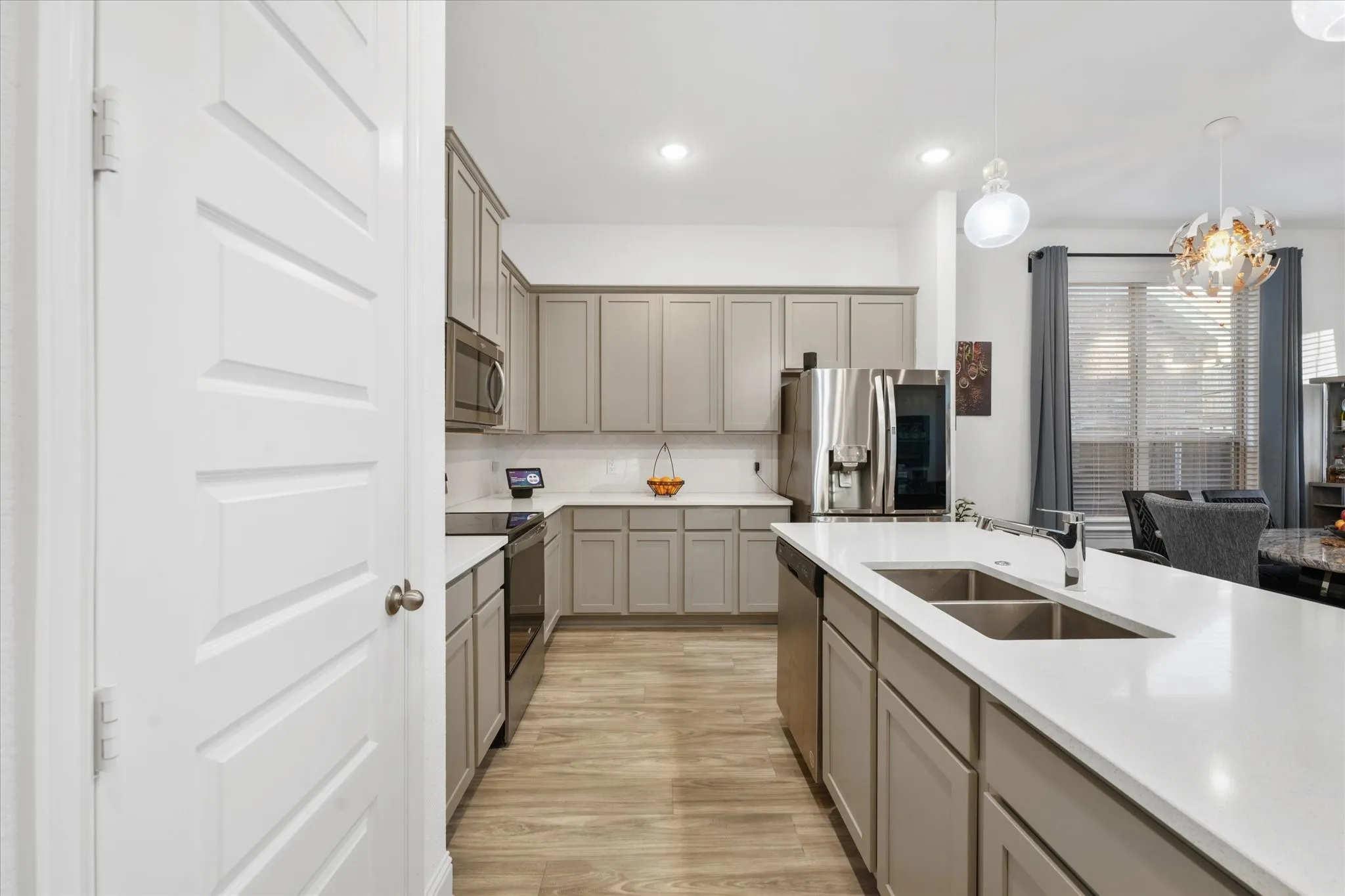Kitchen with light gray cabinetry, stainless steel appliances, wood-finish flooring, white countertops, and recessed lighting