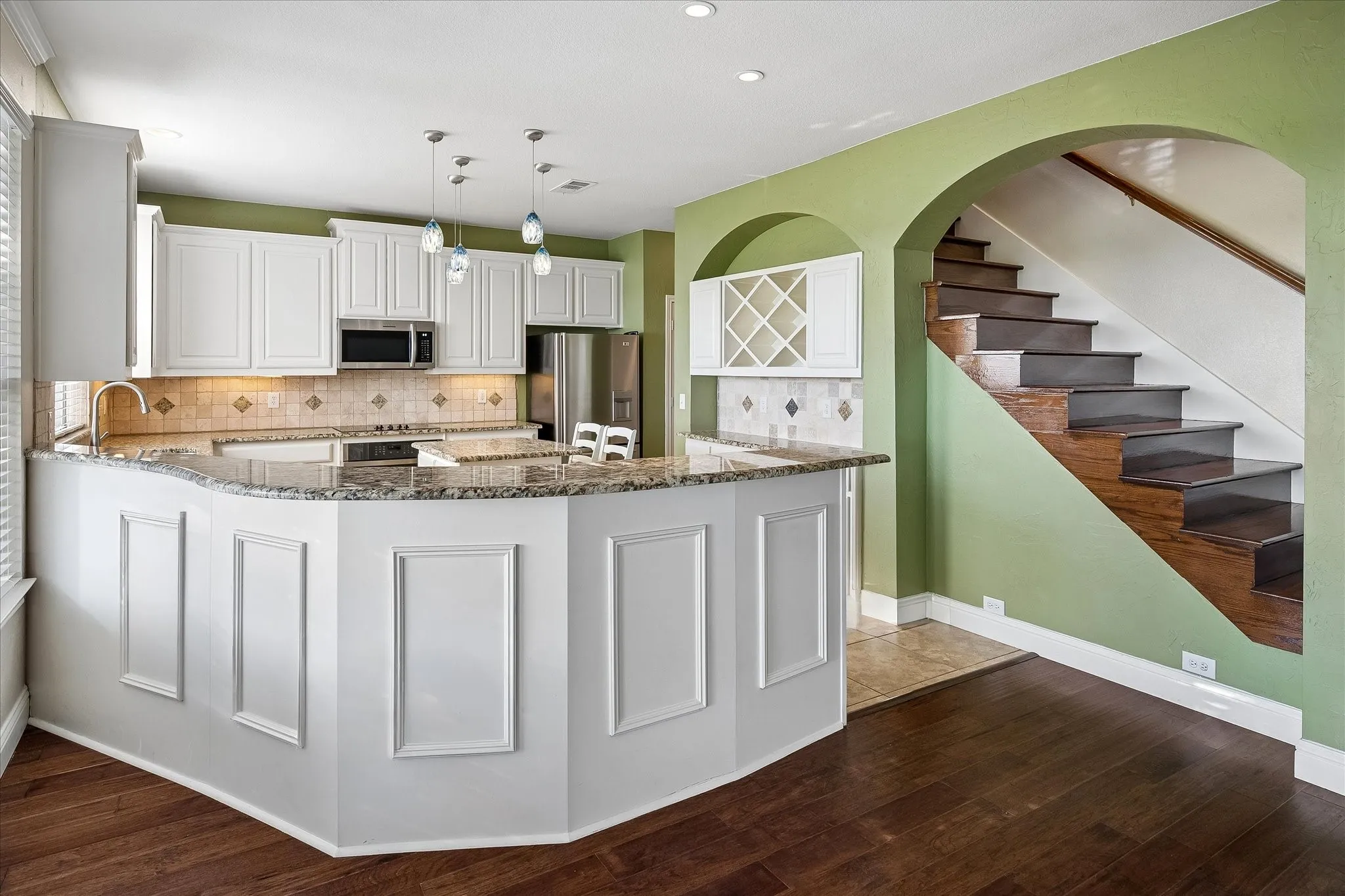 Abundance of cabinets, tile backsplash with decorative inlays, and pendant lights