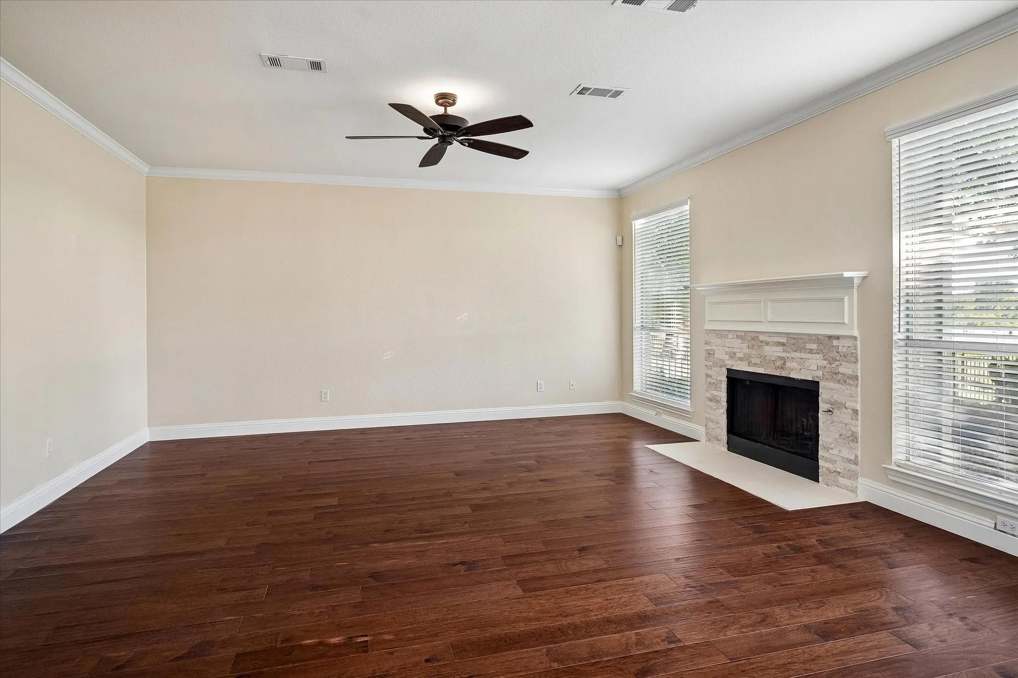 Spacious Family Room with wood burning fireplace, decorative mantle, engineered hardwood flooring, ceiling fan, and 2in faux wood blinds.