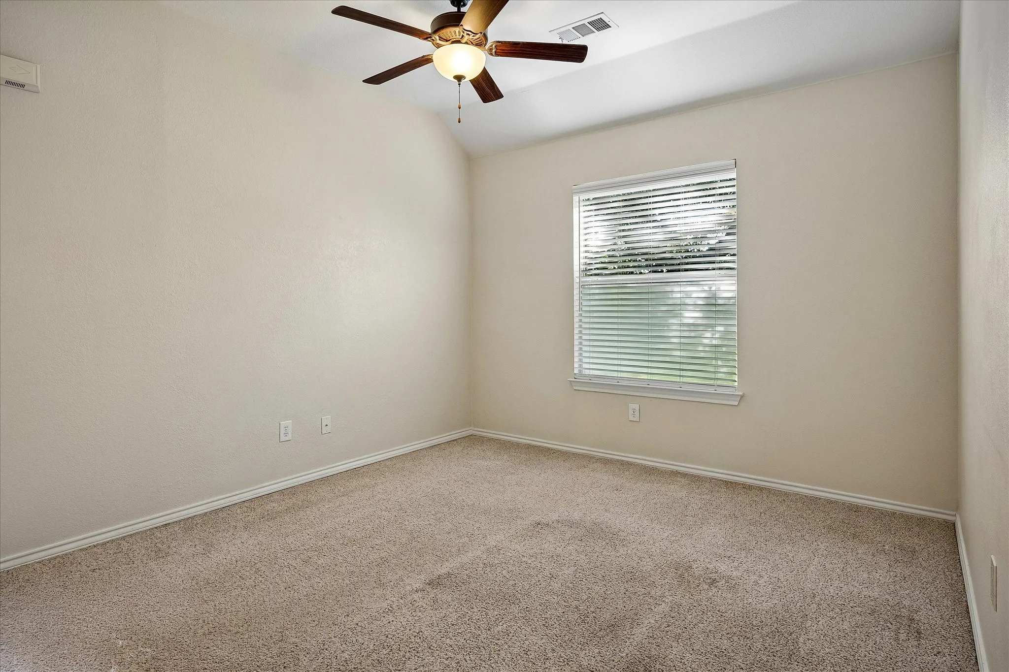 Flexible Living Area with a ceiling fan, 2in faux wood blinds and carpet.