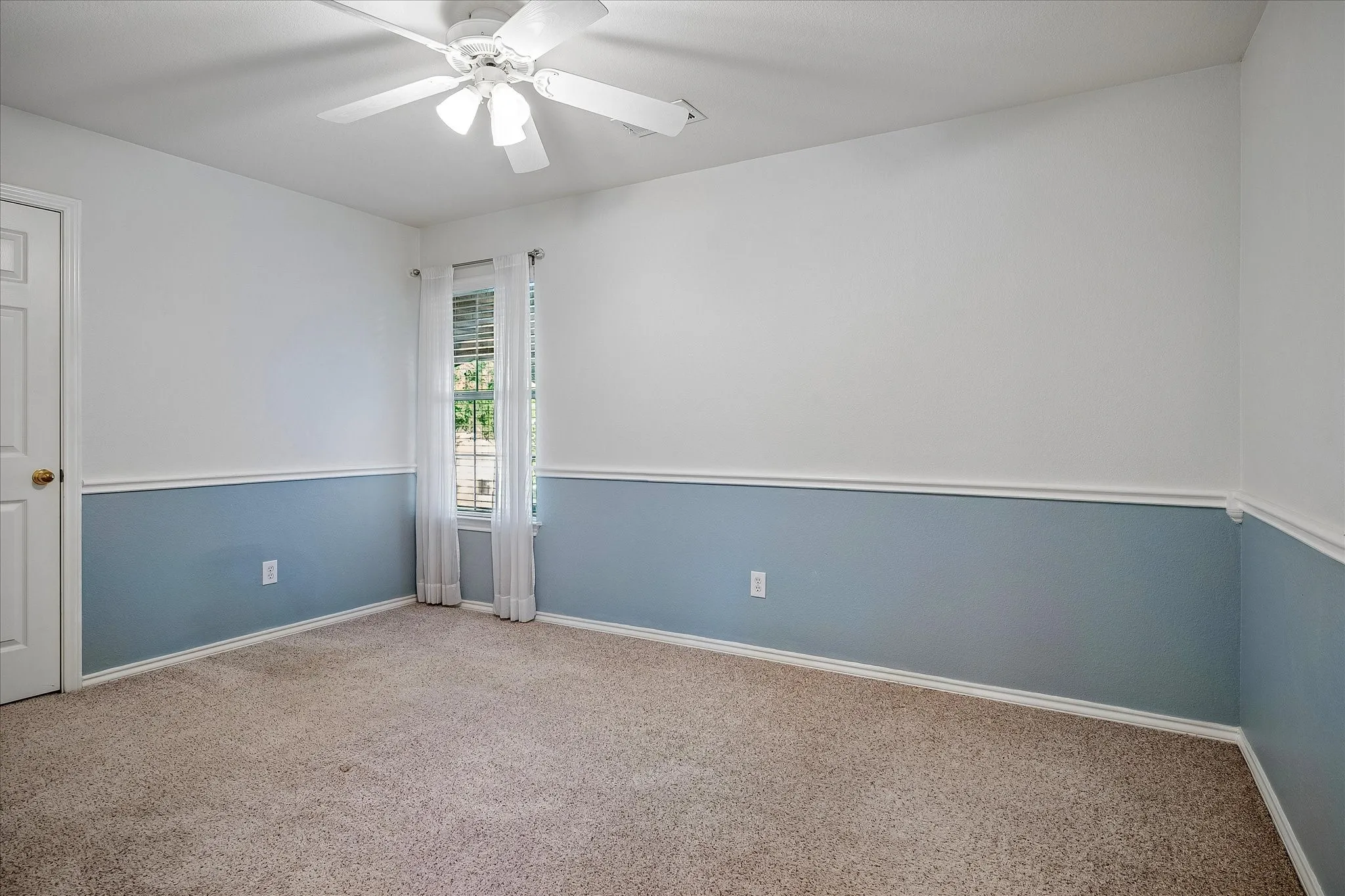 Secondary bedroom has a ceiling fan, closet, chair railing, 2in faux wood blinds and carpet.
