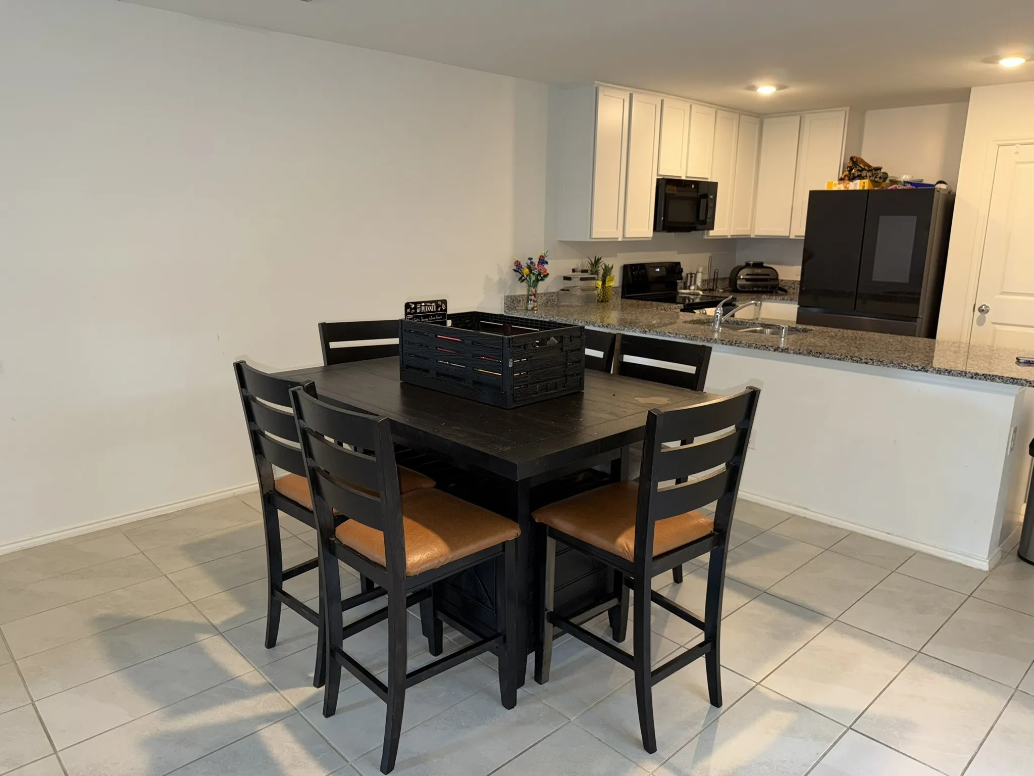 Kitchen featuring white upper cabinetry, black appliances, a double basin sink, and granite countertops