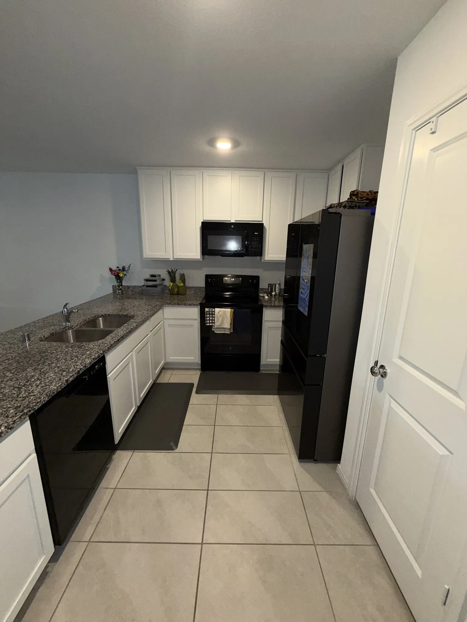 U-shaped kitchen with white cabinetry and dark speckled countertops