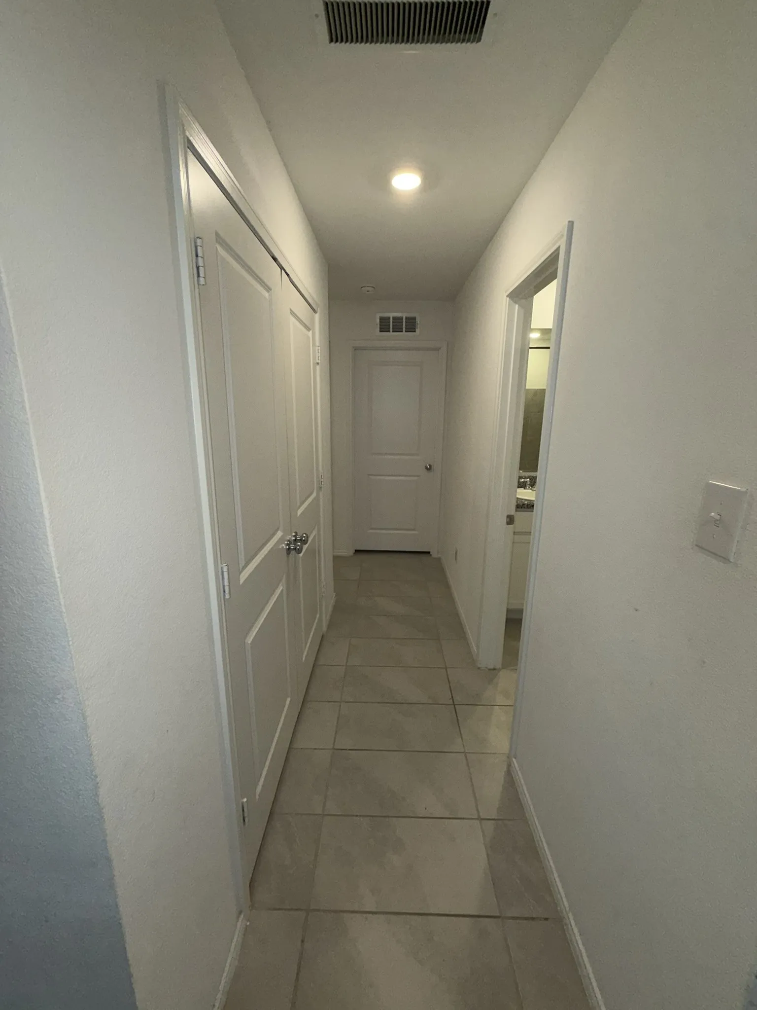 Hallway featuring recessed lighting, tiled flooring, white panel doors, and a neutral color palette