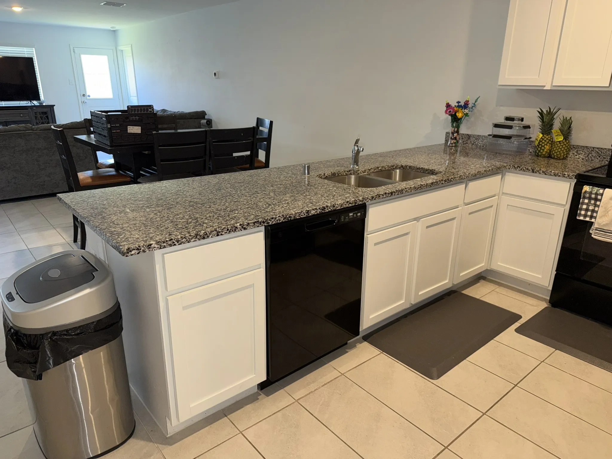 Kitchen island with granite-finish countertop, dual basin sink, and black dishwasher