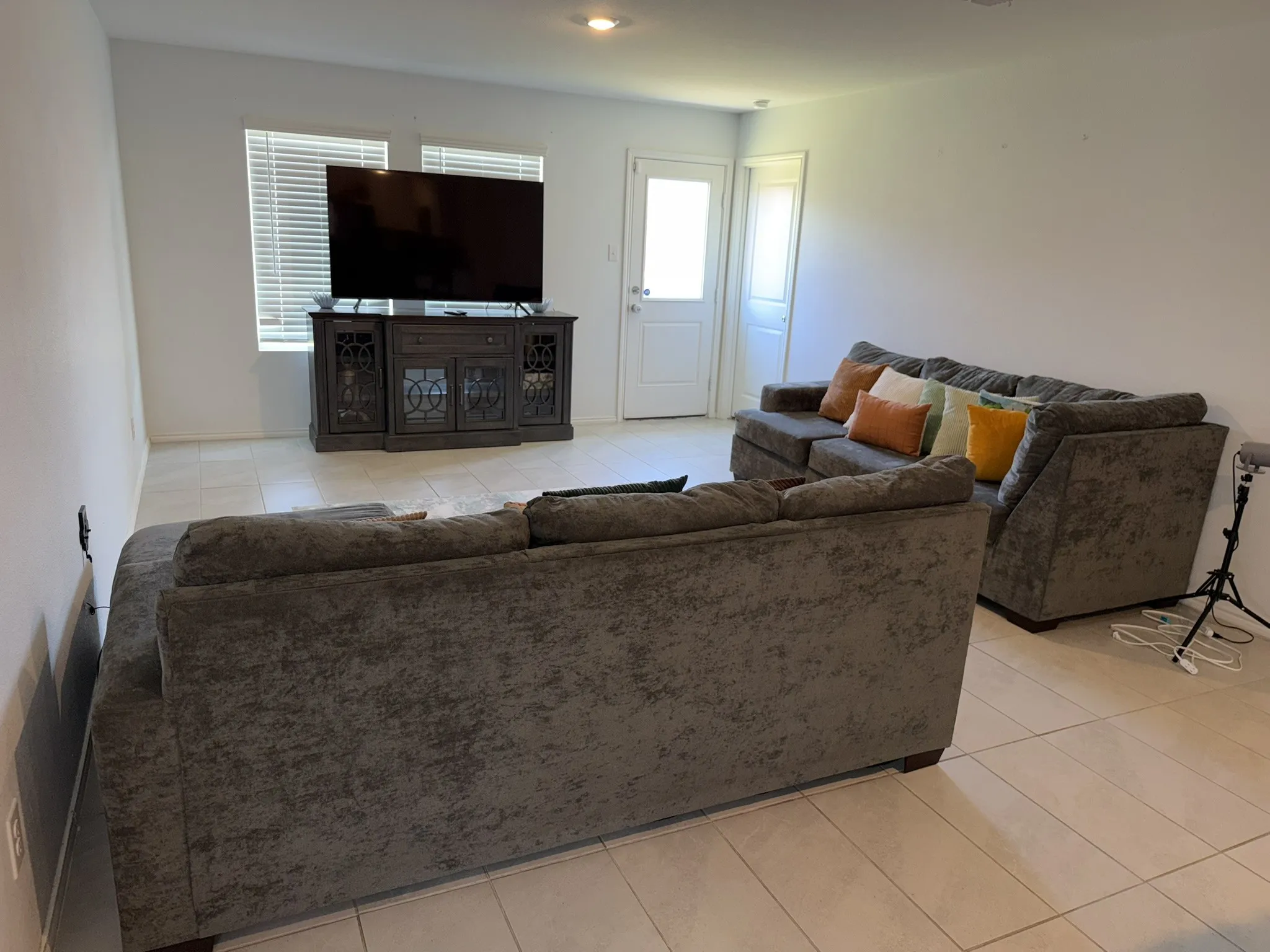 Open-concept living space featuring light-toned tile flooring, recessed lighting, and a white wall finish