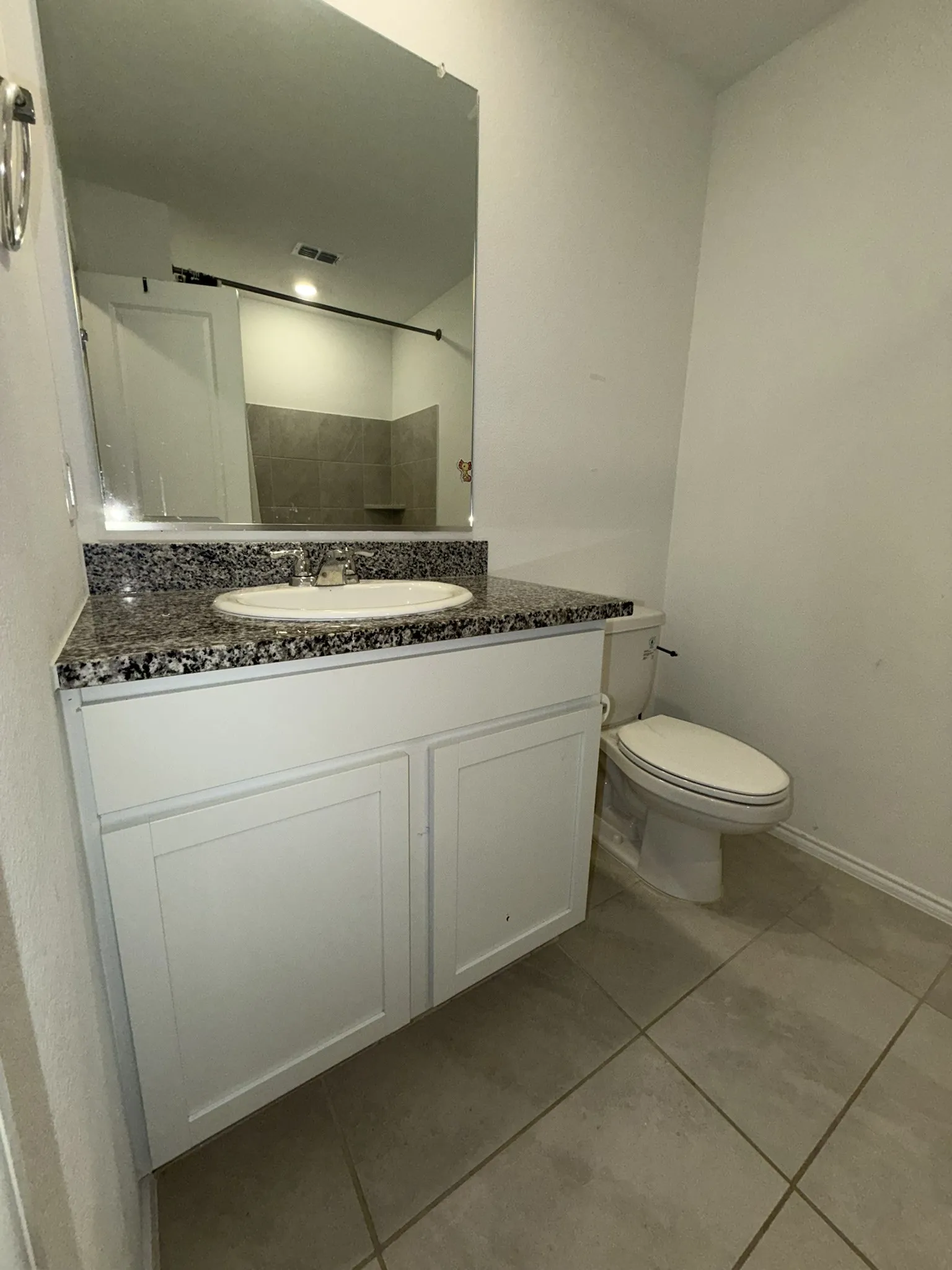 Bathroom featuring a white vanity with panel-front cabinetry, a speckled countertop, an oval undermount sink with a chrome faucet, and a large wall-mounted mirror